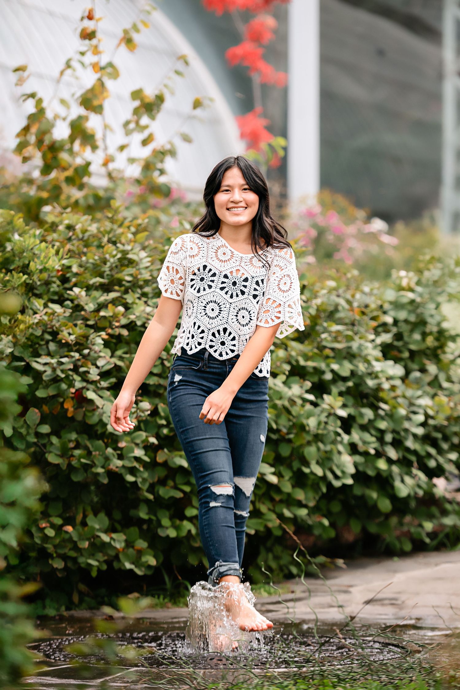 Candid sequence of joyful puddle splashing near garden bushes in summer attire.