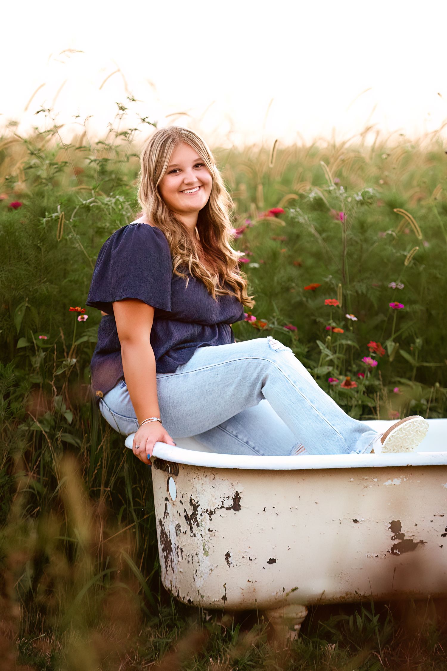 Vintage bathtub in a wildflower field during golden hour photography session.