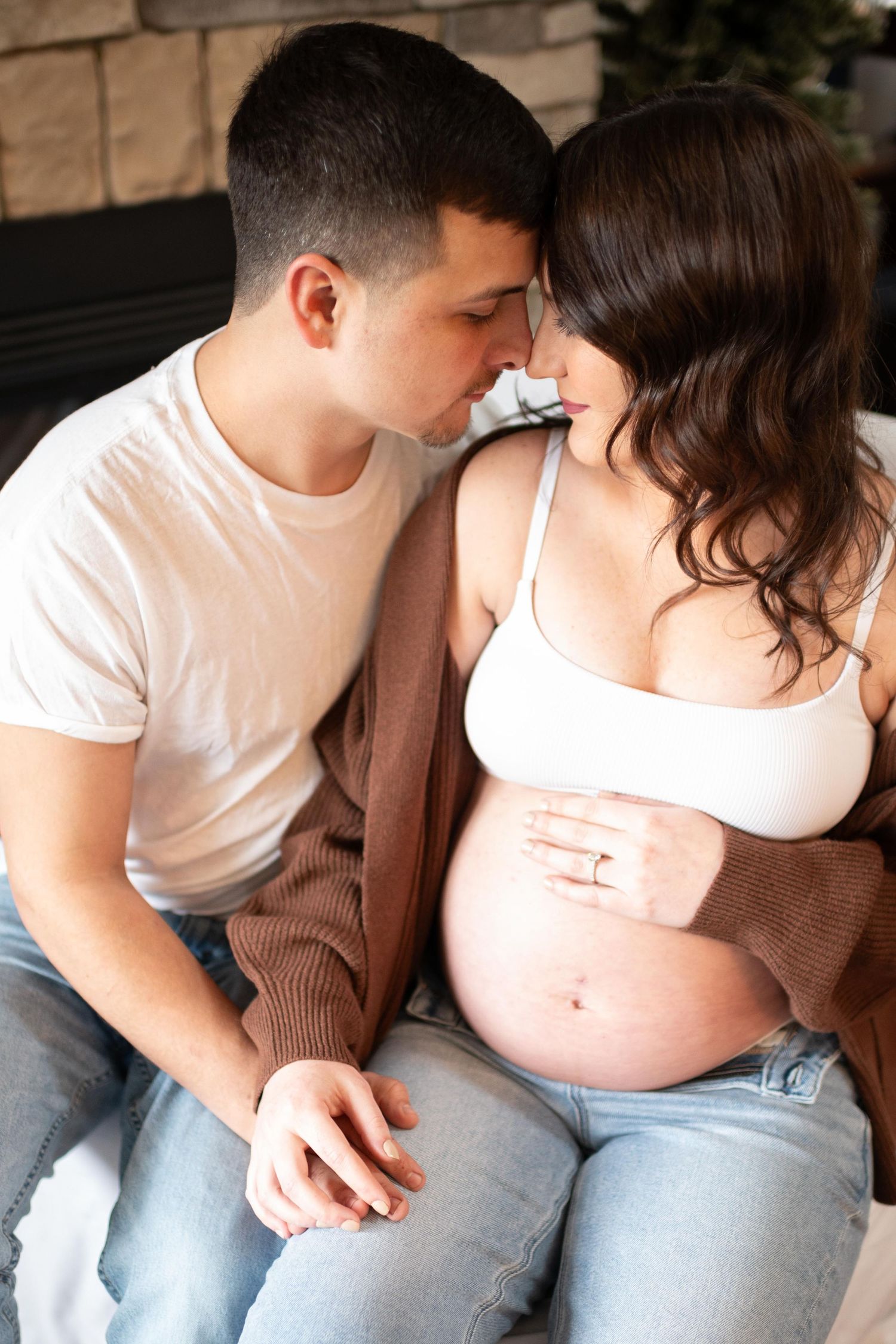 An intimate maternity photo session showing a couple relaxing together indoors.