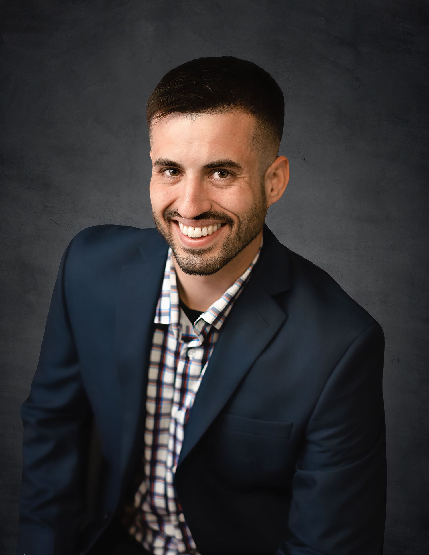 Professional portraits of a person in navy suit and checkered shirt.