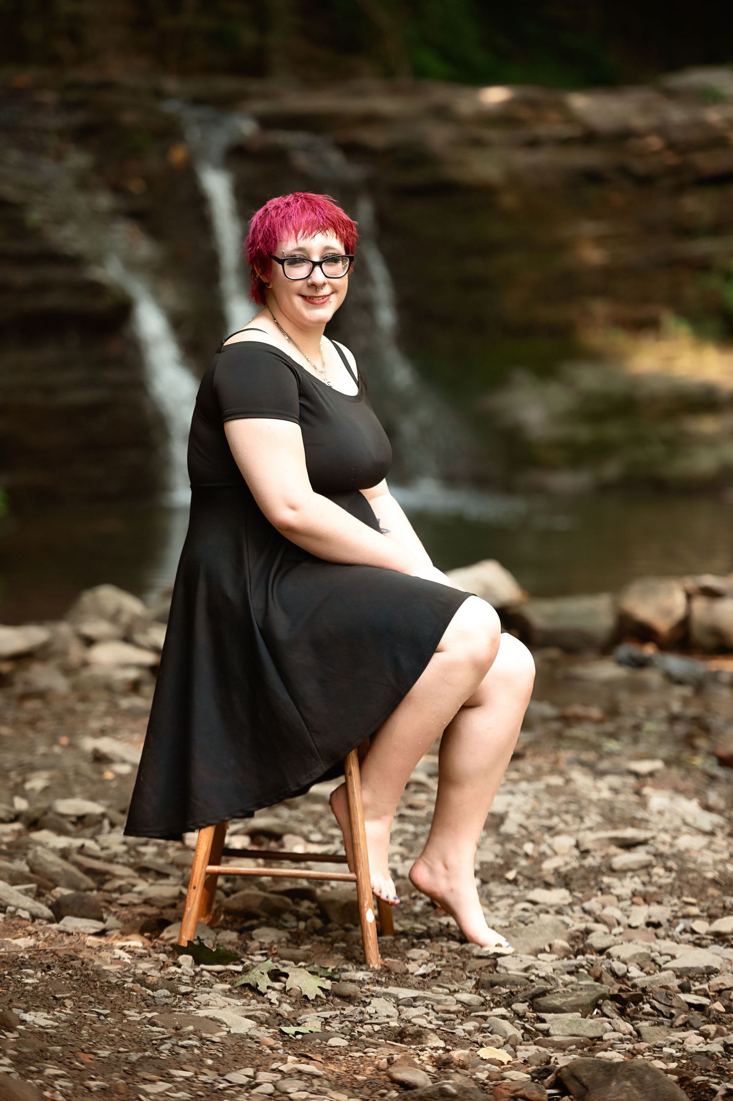 Artistic portraits on rocky terrain near a waterfall.