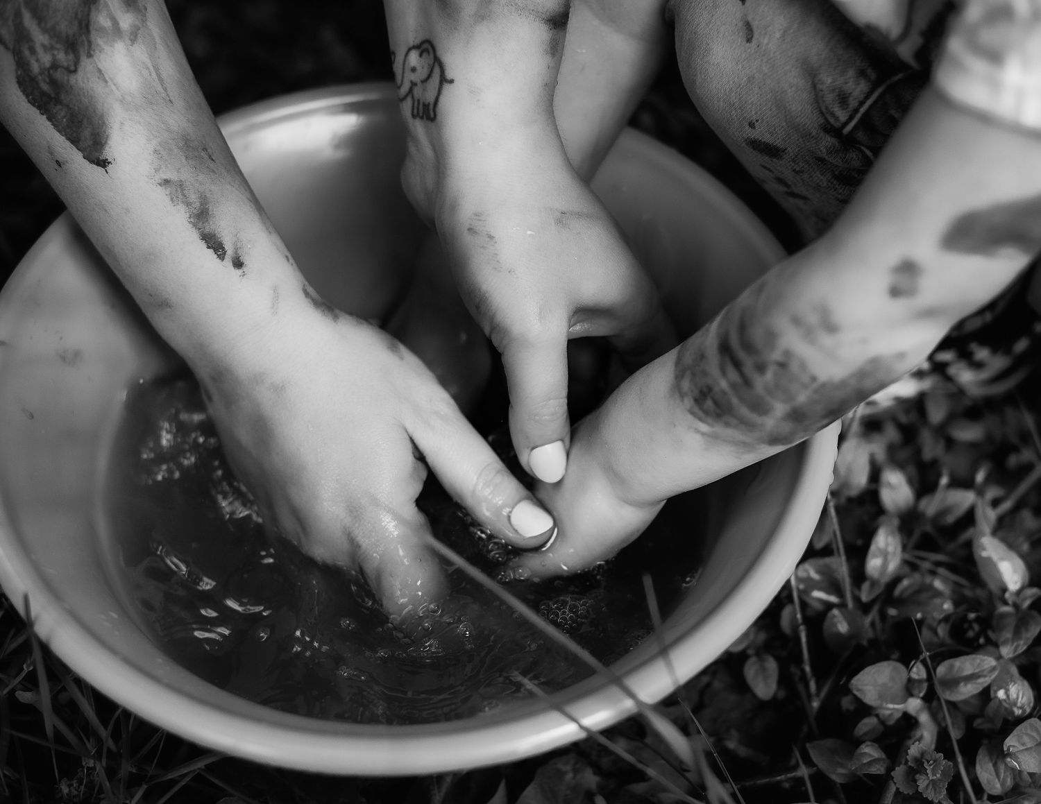Hands playing in dark muddy water showing messy outdoor play.