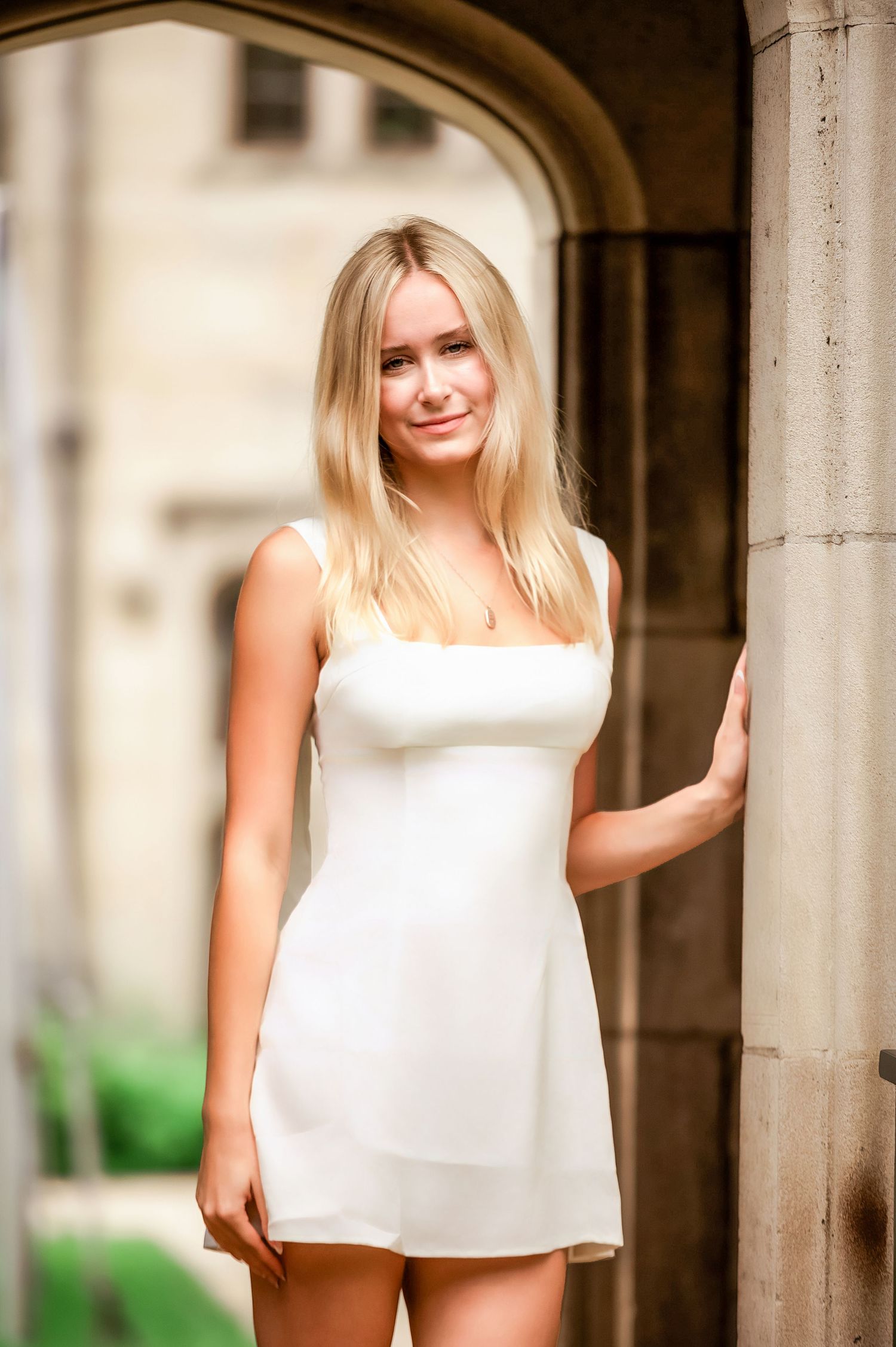 Multiple poses in a white sleeveless top against classic stone architecture and columns.