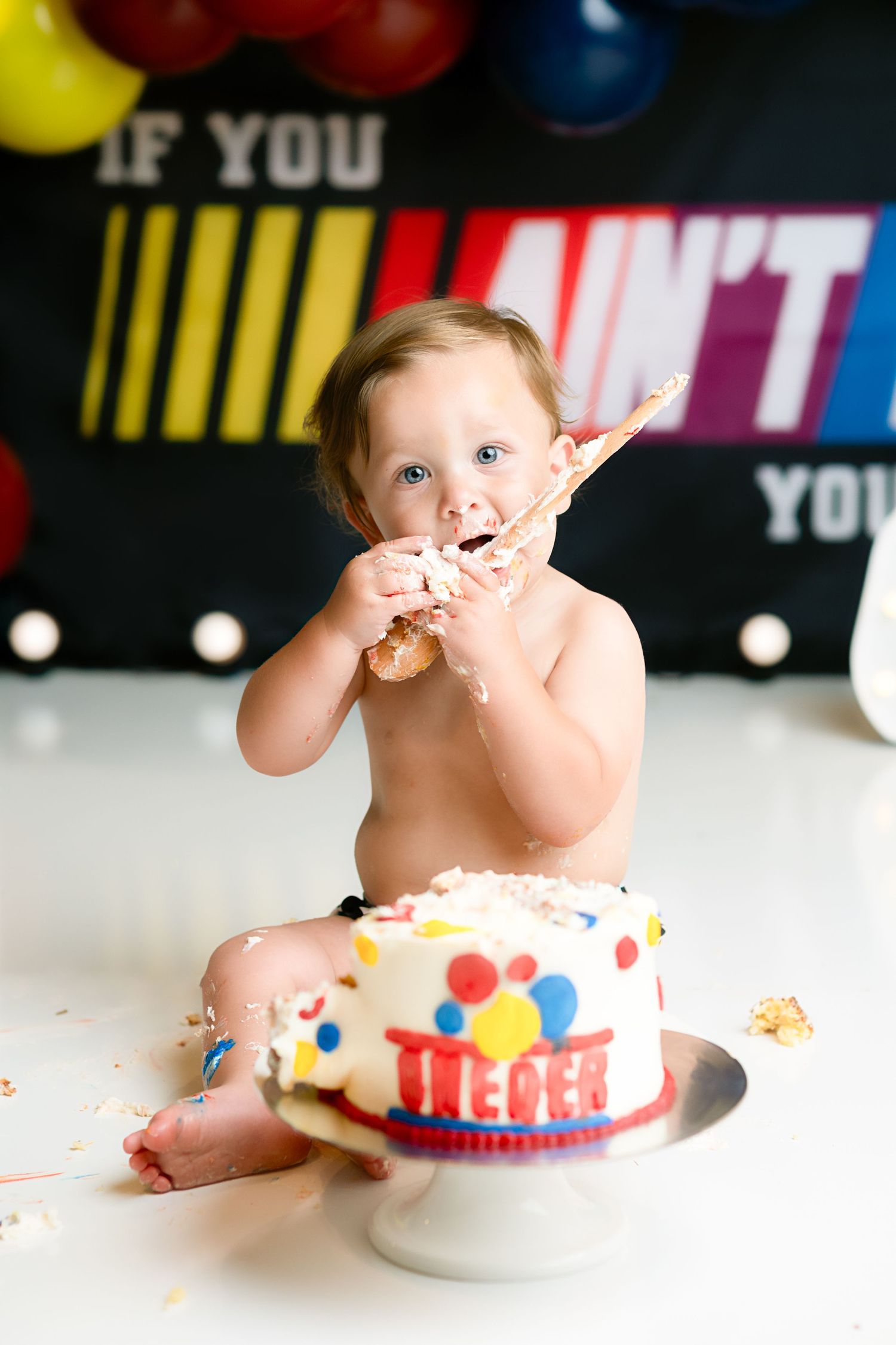 A colorful cake smash photo session with balloons and festive decorations.