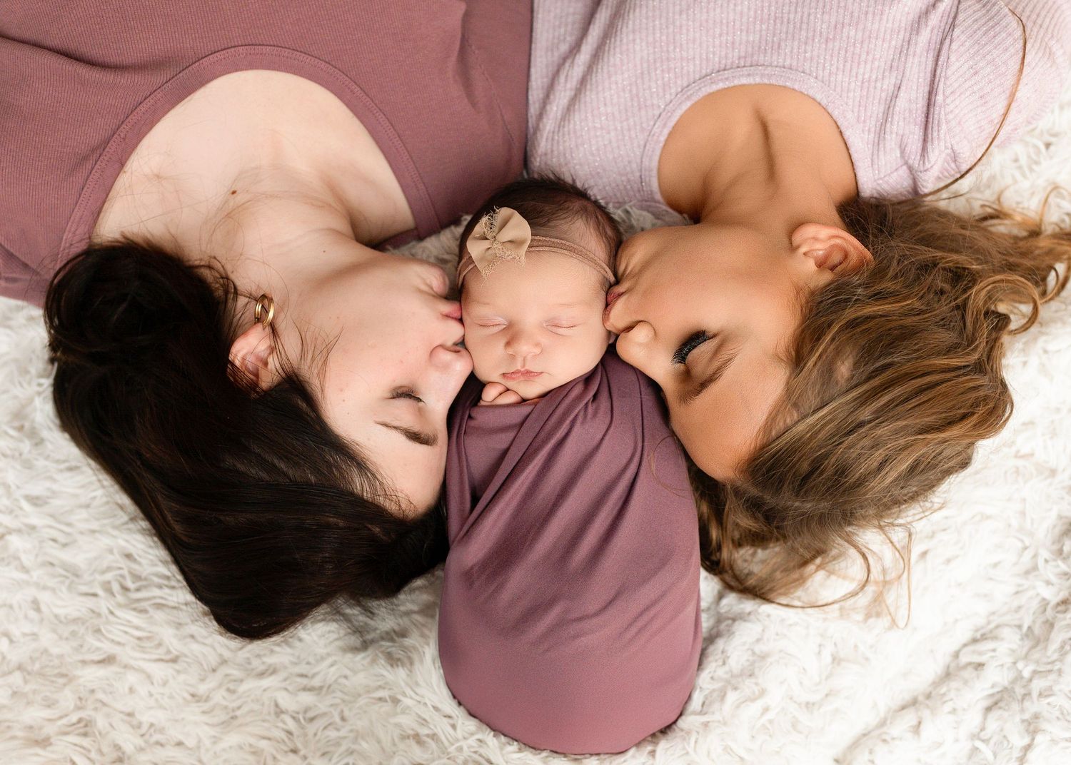 Sleeping infant in mauve wrap on soft white bedding shown in multiple gentle poses.