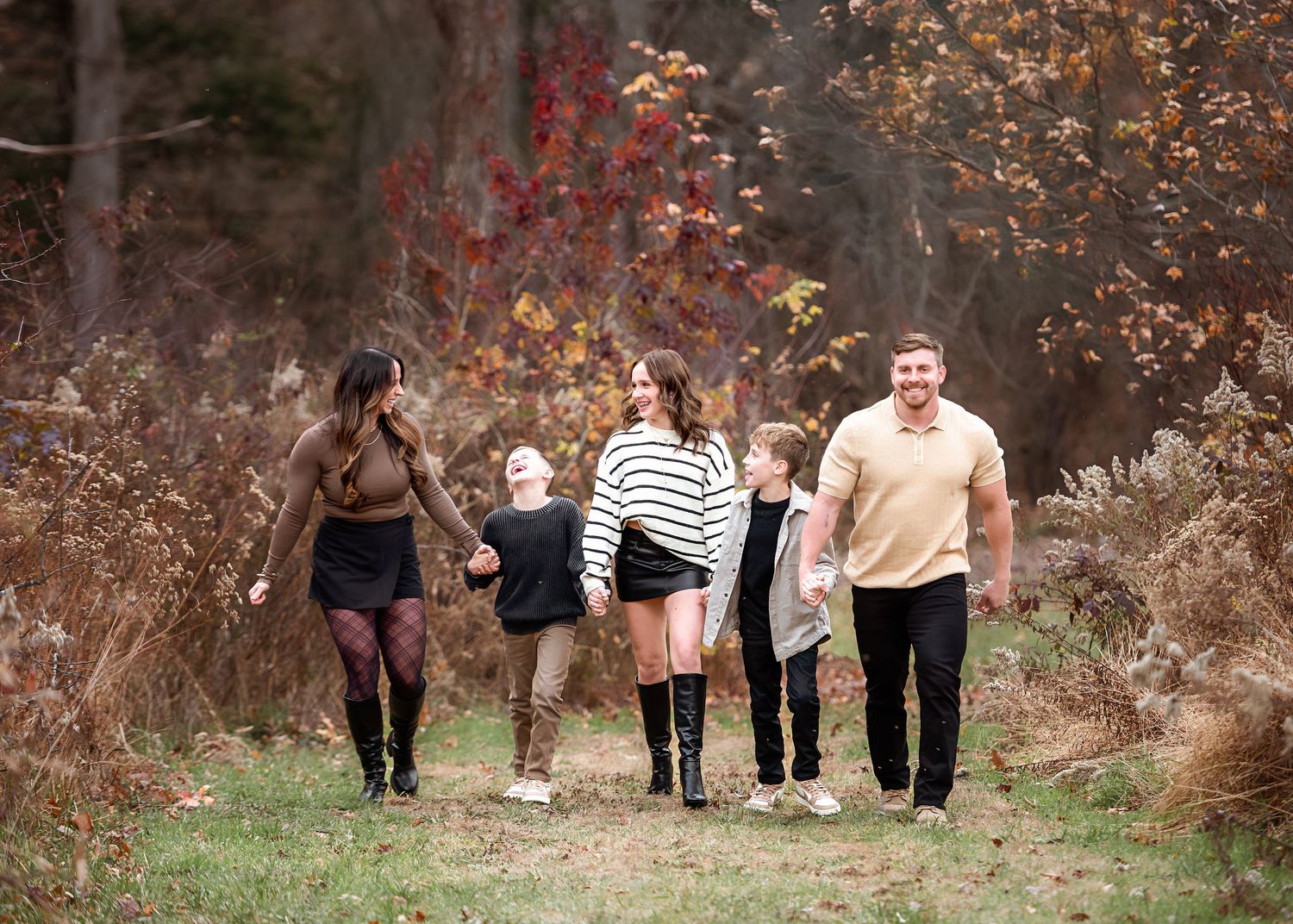 A group walks together on a nature trail during autumn with colorful fall foliage in the background.