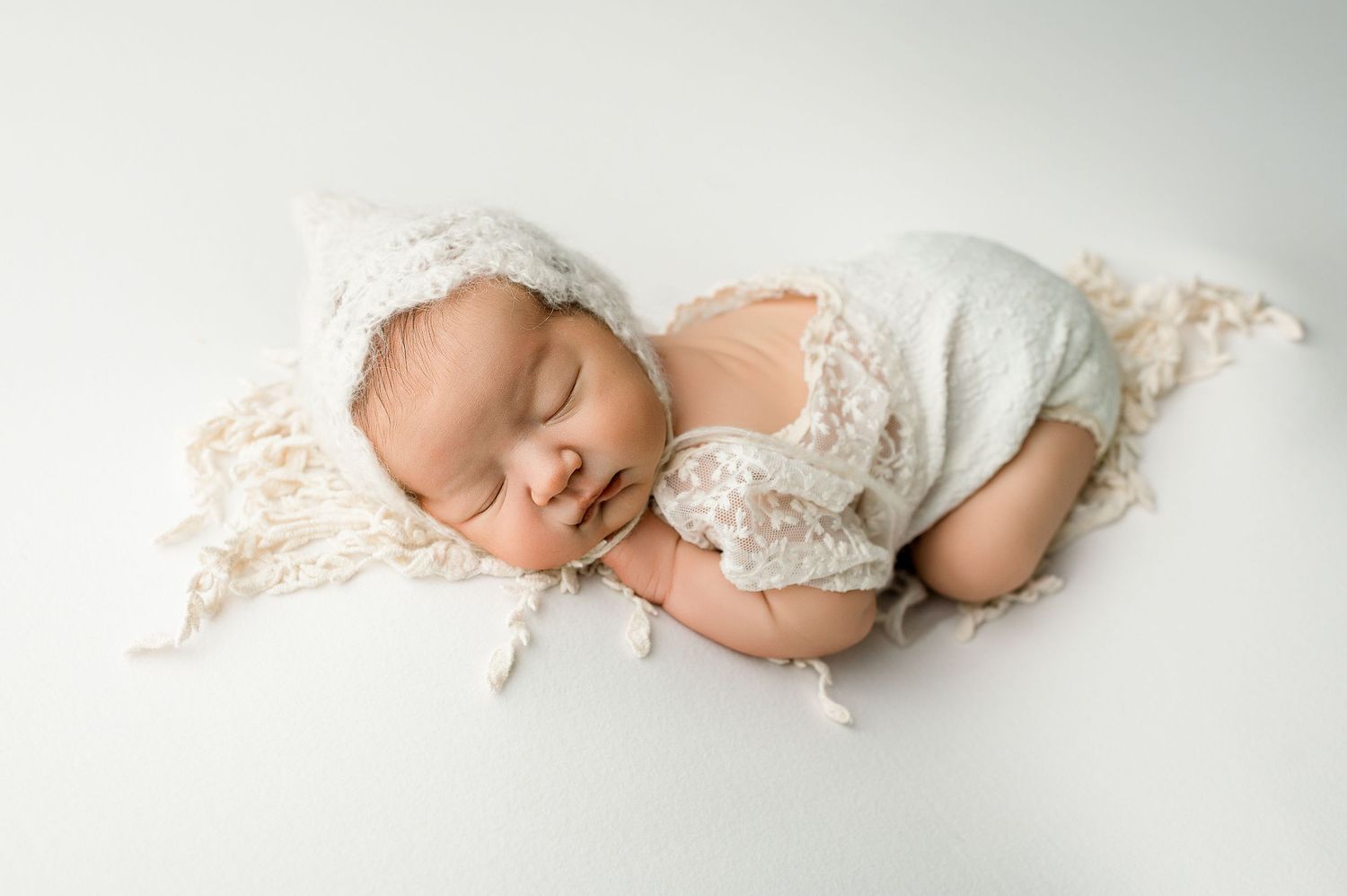 A series of four connected newborn baby photos showing peaceful sleeping poses in soft white lace outfits.