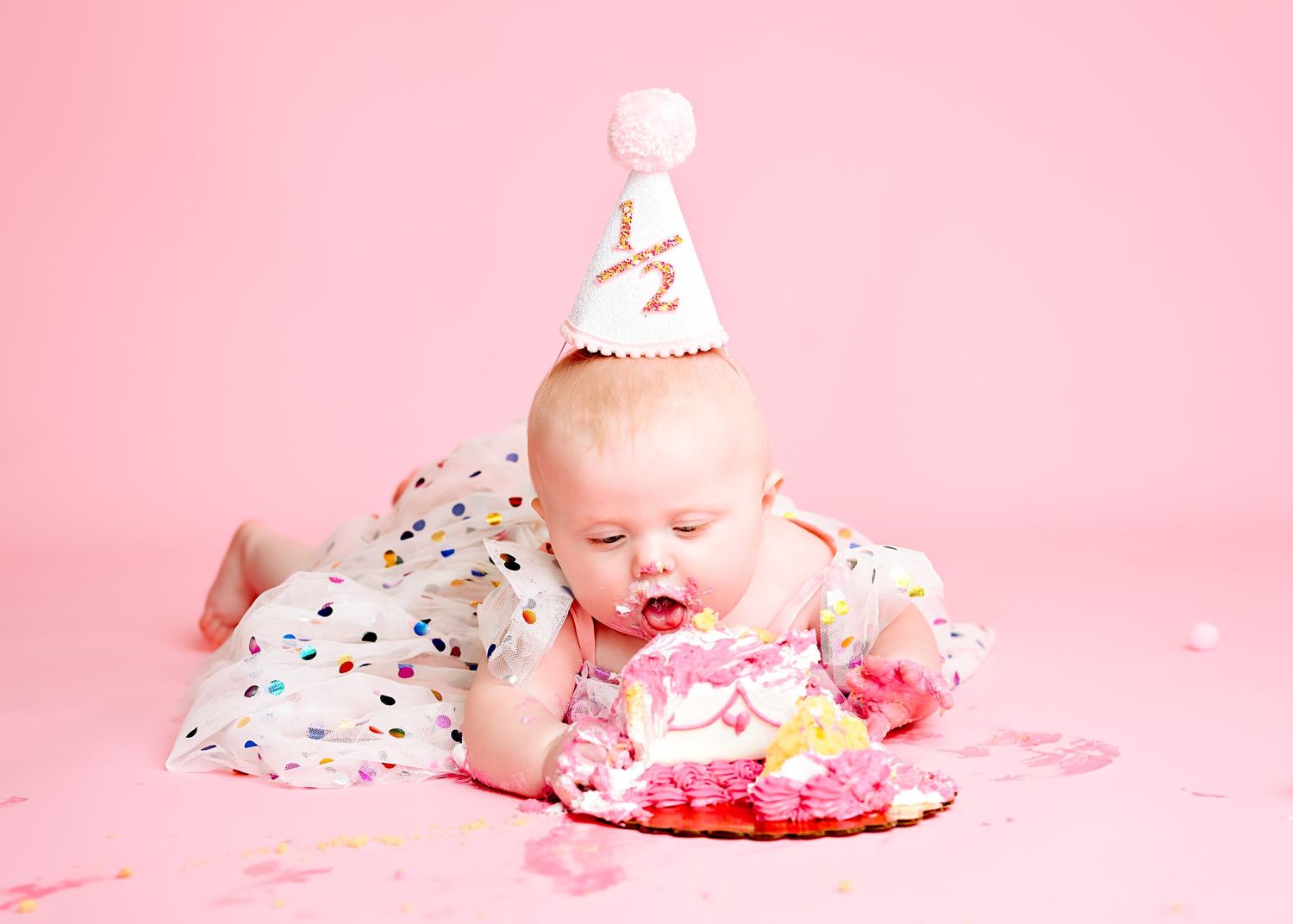 Pink themed cake smash photography setup with sprinkles and decorative elements.