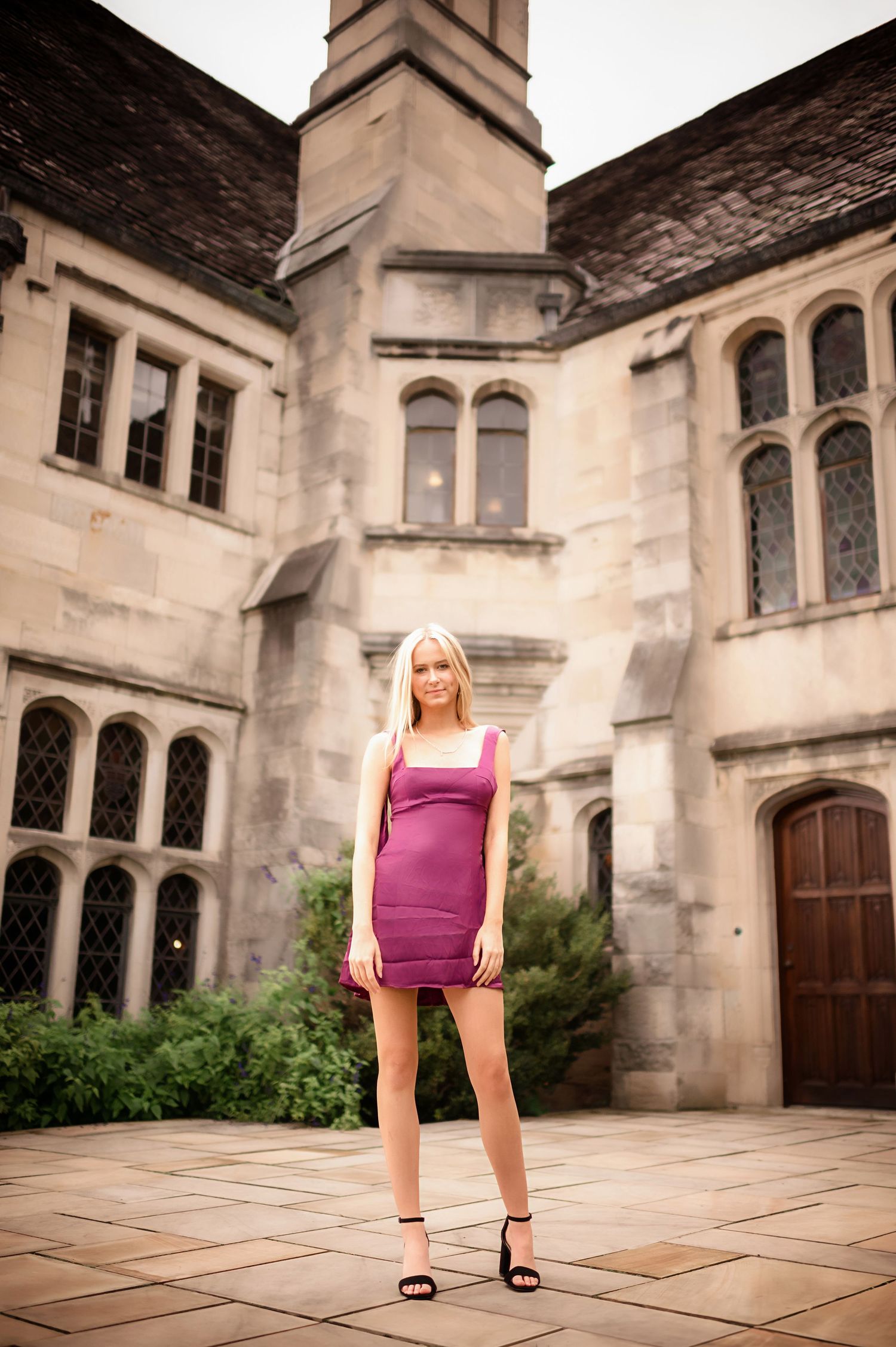 A fashion portrait against Gothic stone architecture with arched windows and detailed masonry.