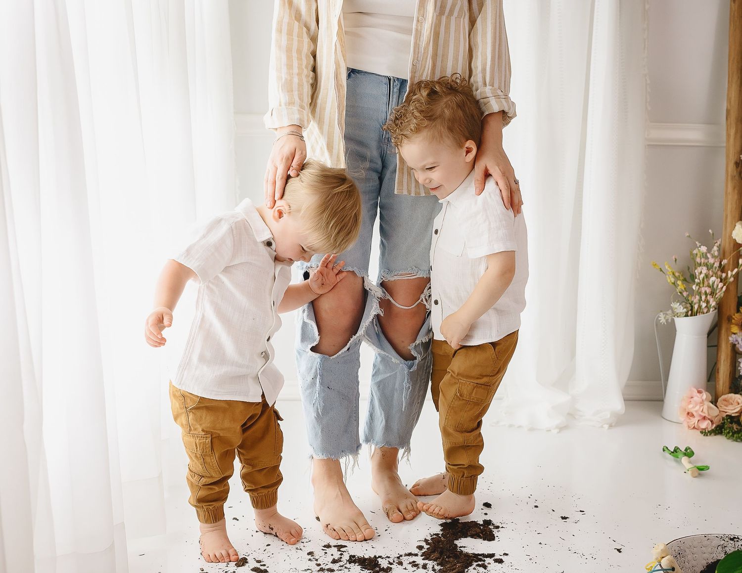 A playful indoor family scene with white curtains and natural light.