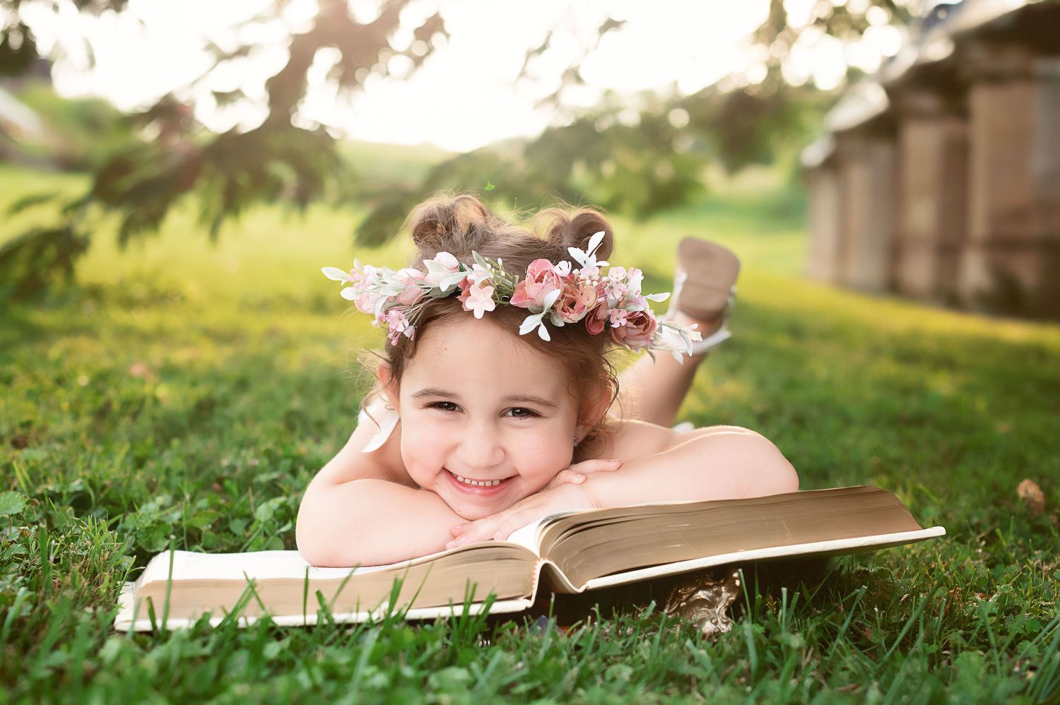 Whimsical outdoor photo session with books and floral elements in green grass.