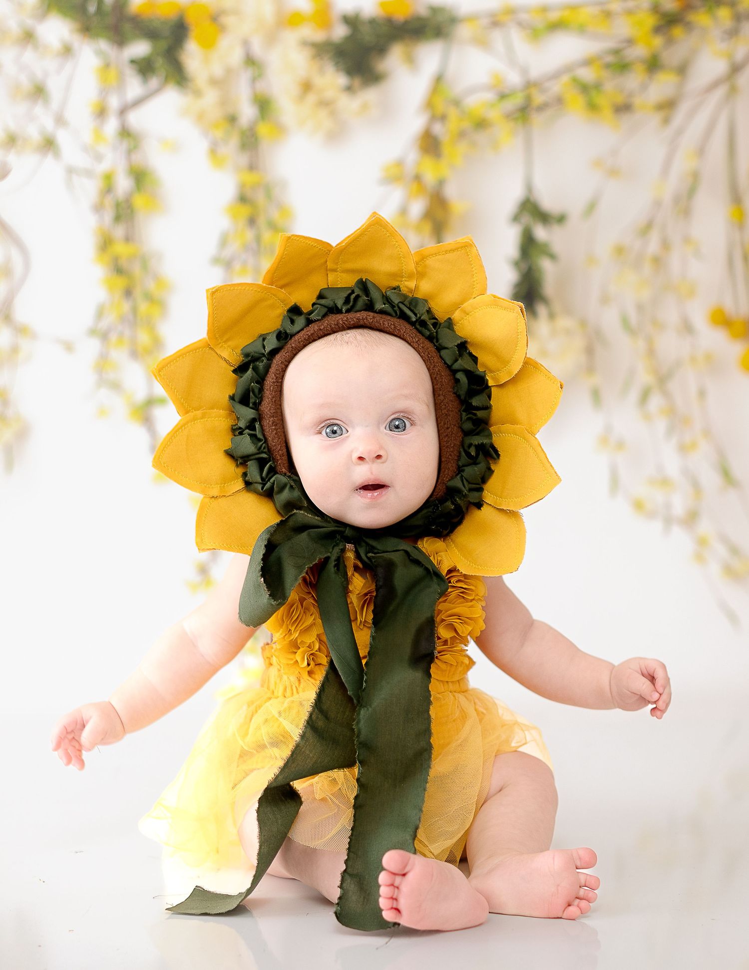 Baby dressed in adorable sunflower costume against white background.