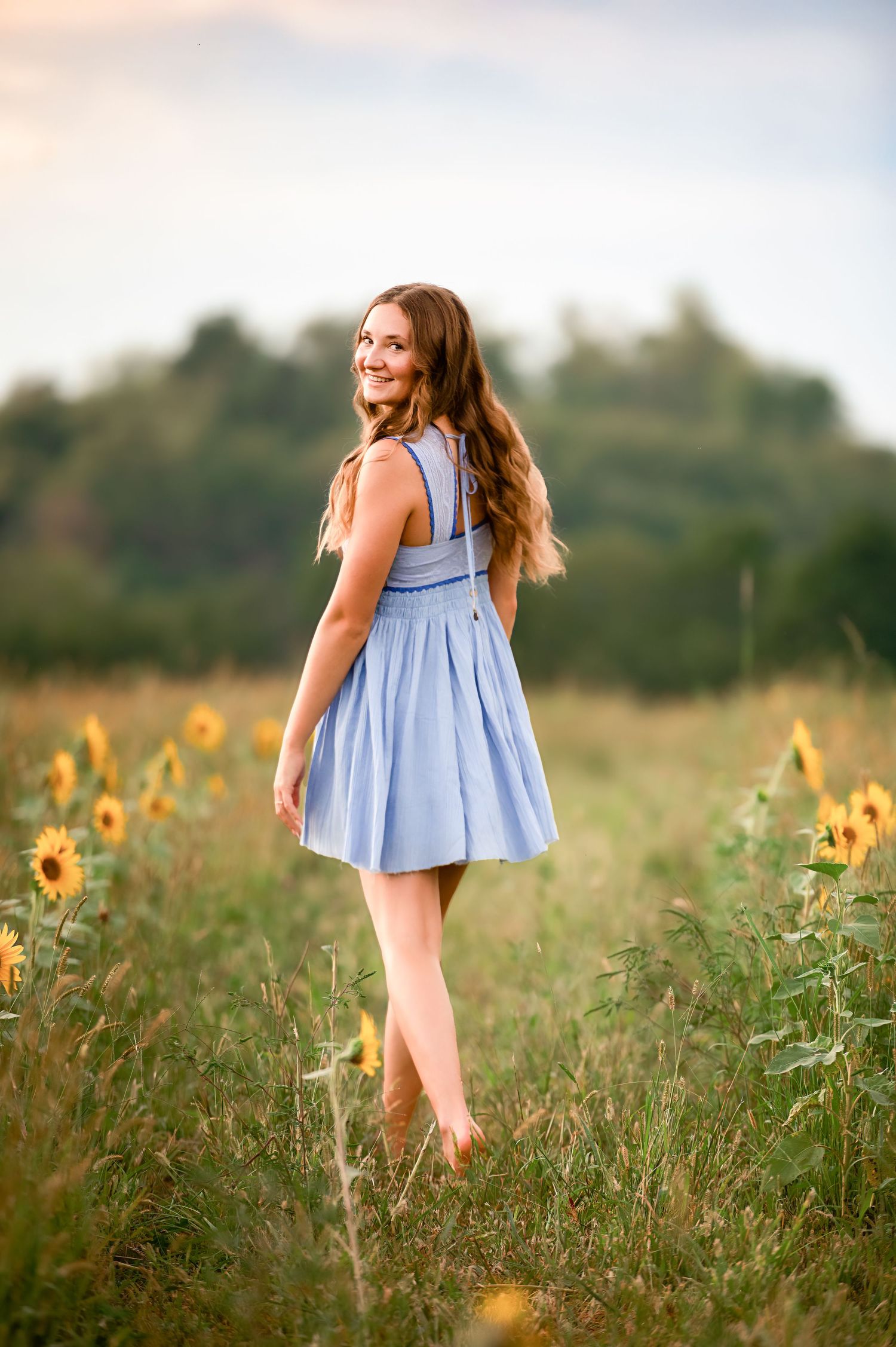 Light blue dress twirling among sunflowers in a summer field.