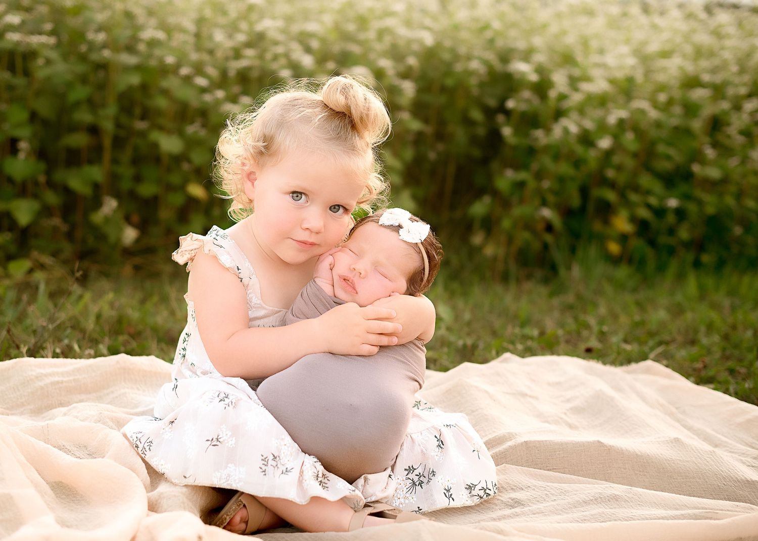 Outdoor portrait session on beige blanket in natural garden setting.
