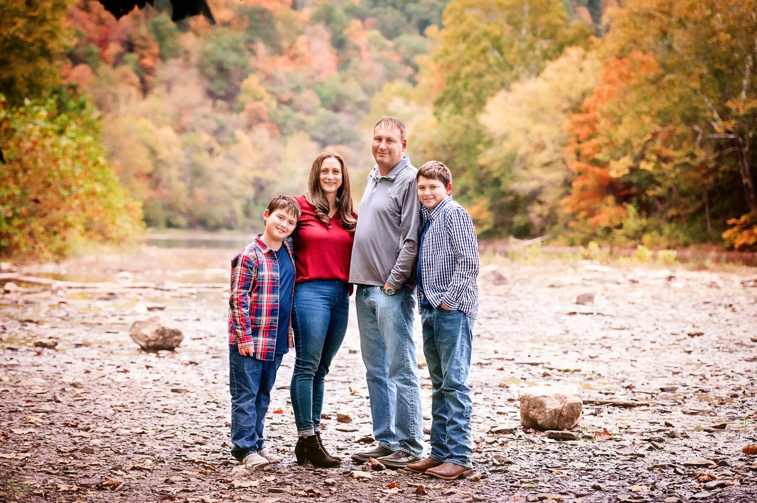 Family walking together on fallen leaves during autumn photo session.