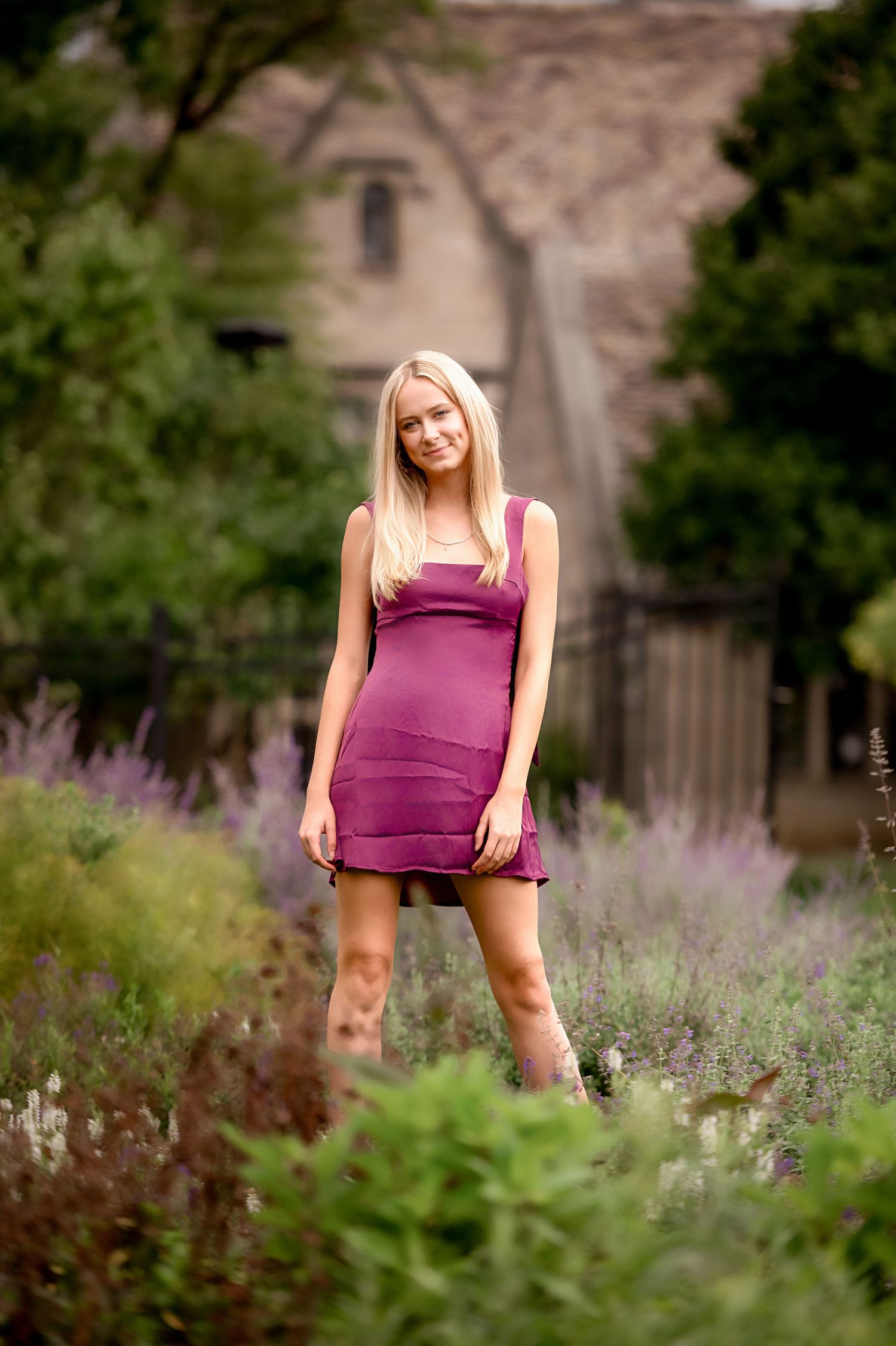 A fashion portrait in a purple dress with lavender flowers and stone building backdrop.
