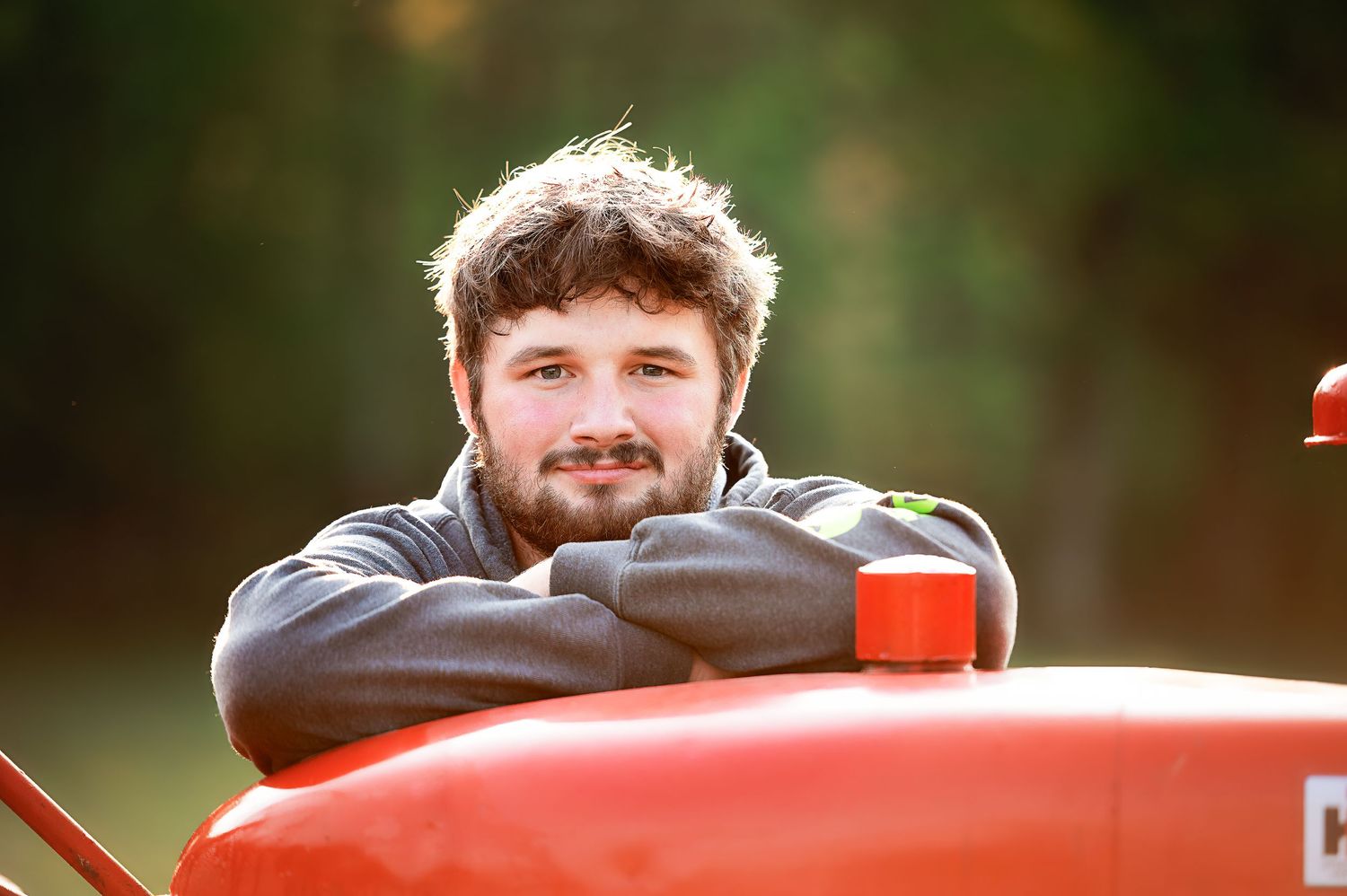 Rural portrait session featuring classic red tractor in green countryside setting.