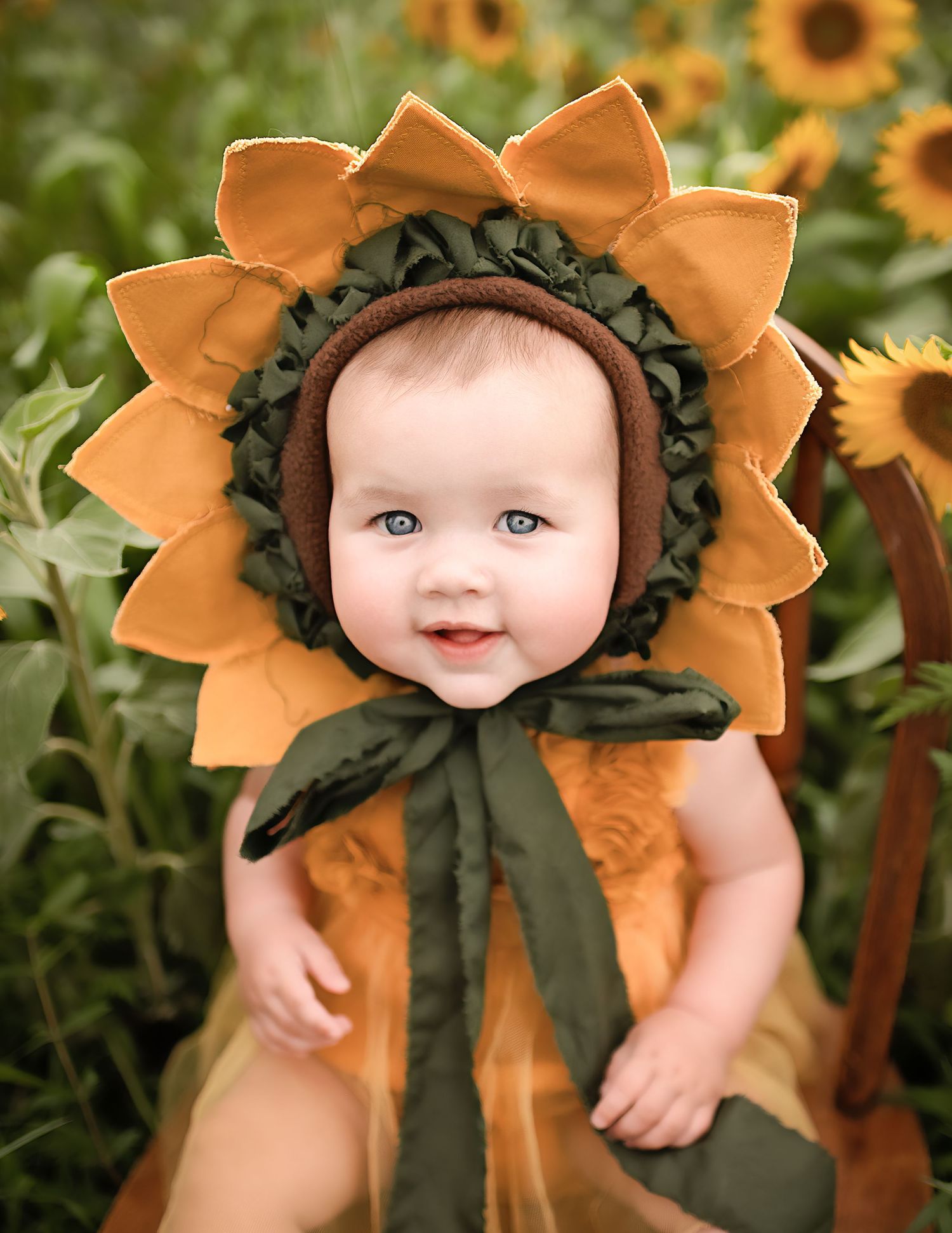 Creative sunflower costume portrait with orange petals and green leaves.