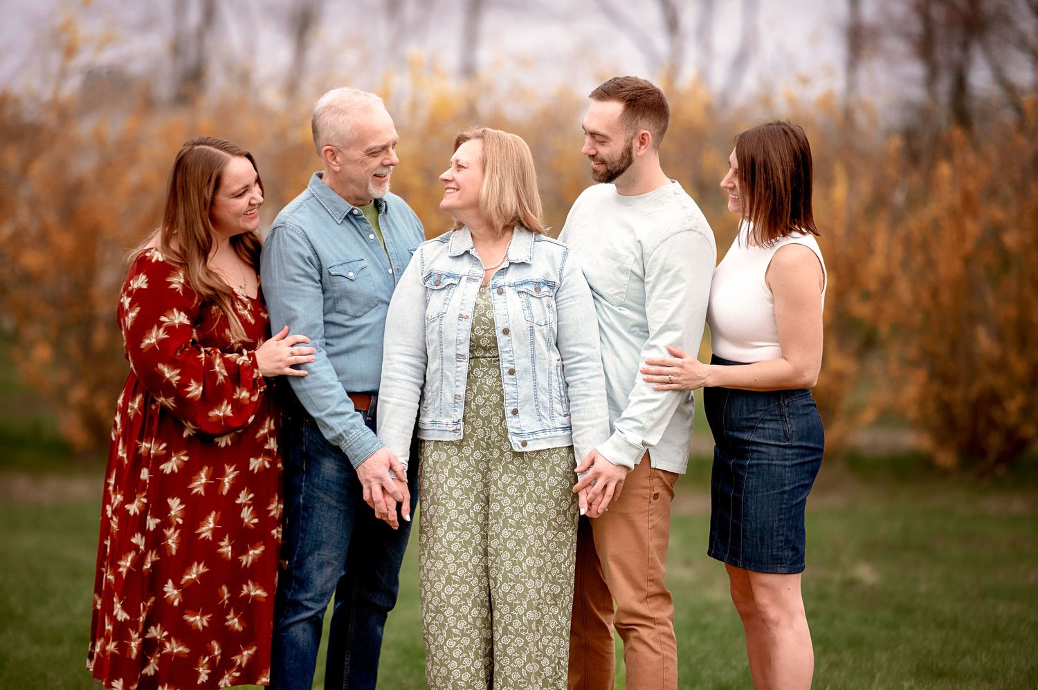 Extended family shares laughs during autumn outdoor photo session.
