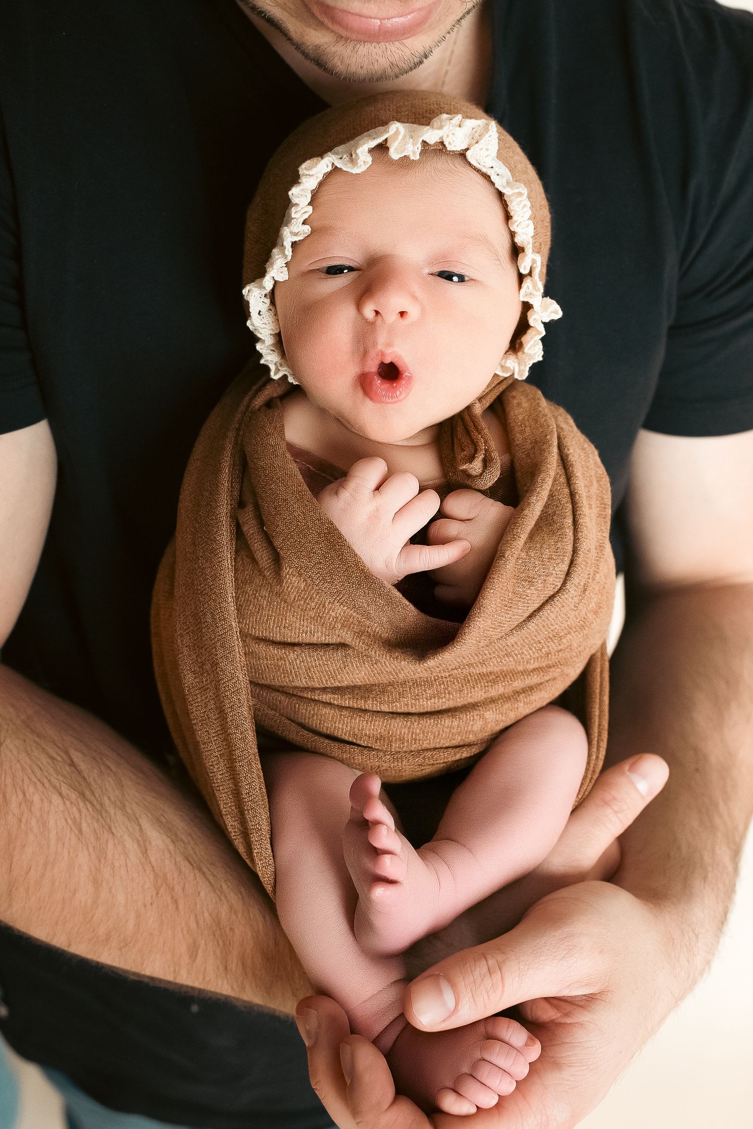 Series of newborn baby photos showing infant wrapped in brown blanket held in parent's arms with different poses and expressions.