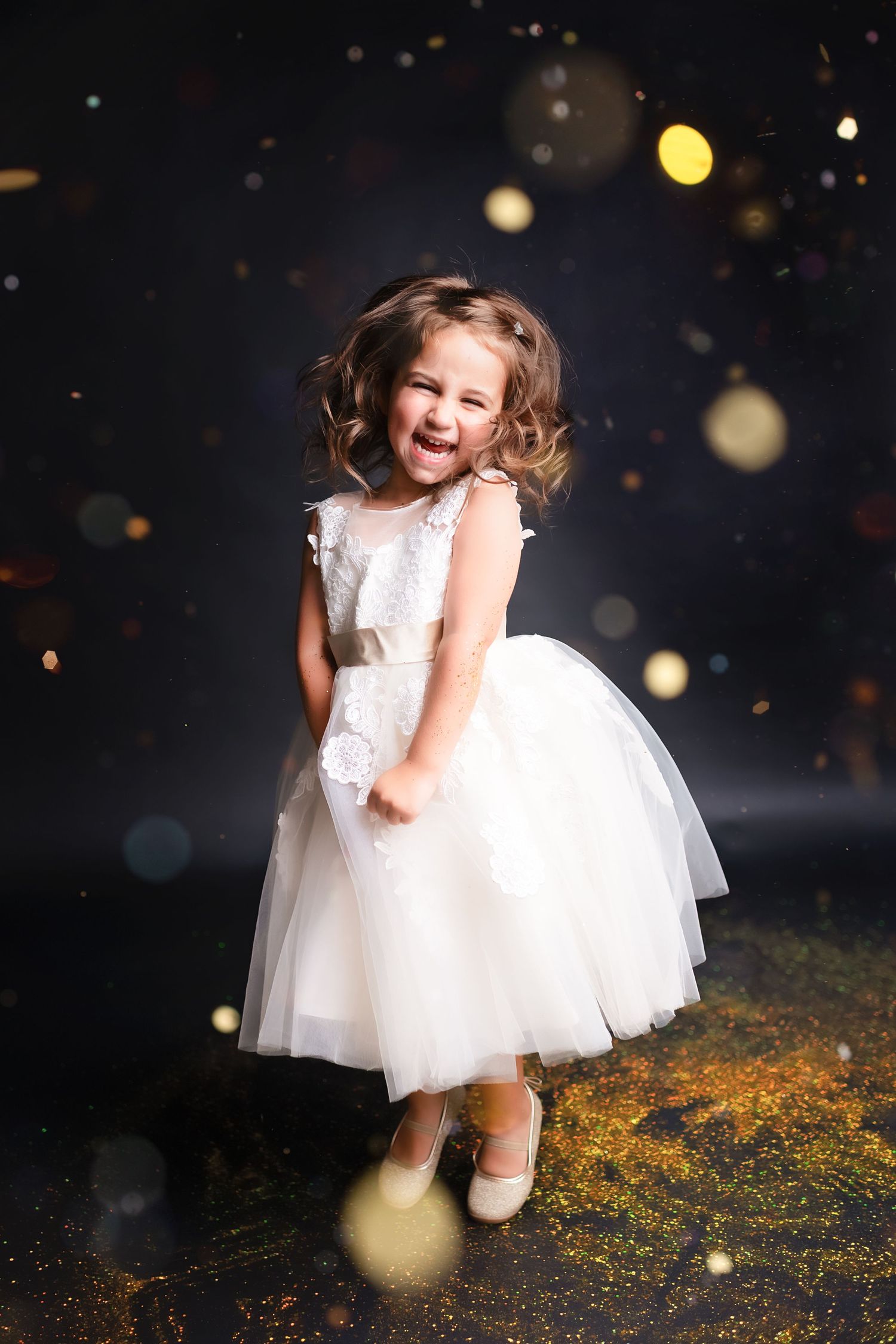 White dress twirl photoshoot with magical glitter and bokeh effects on dark background.
