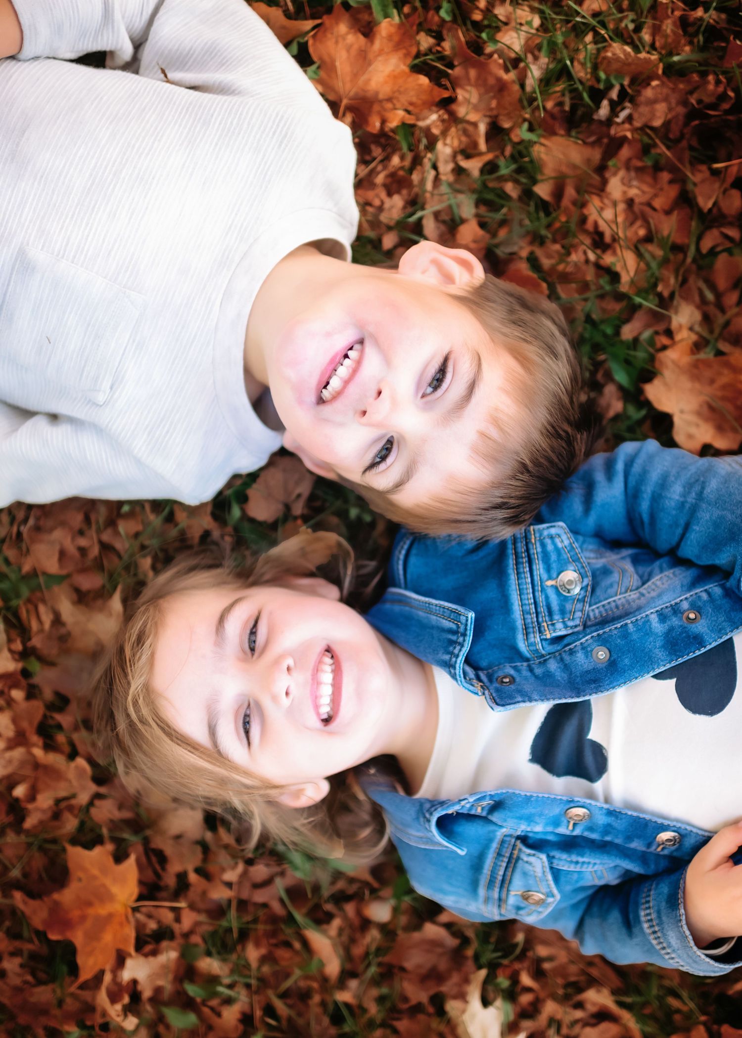 Autumn outdoor photoshoot with fallen leaves and denim jacket styling.