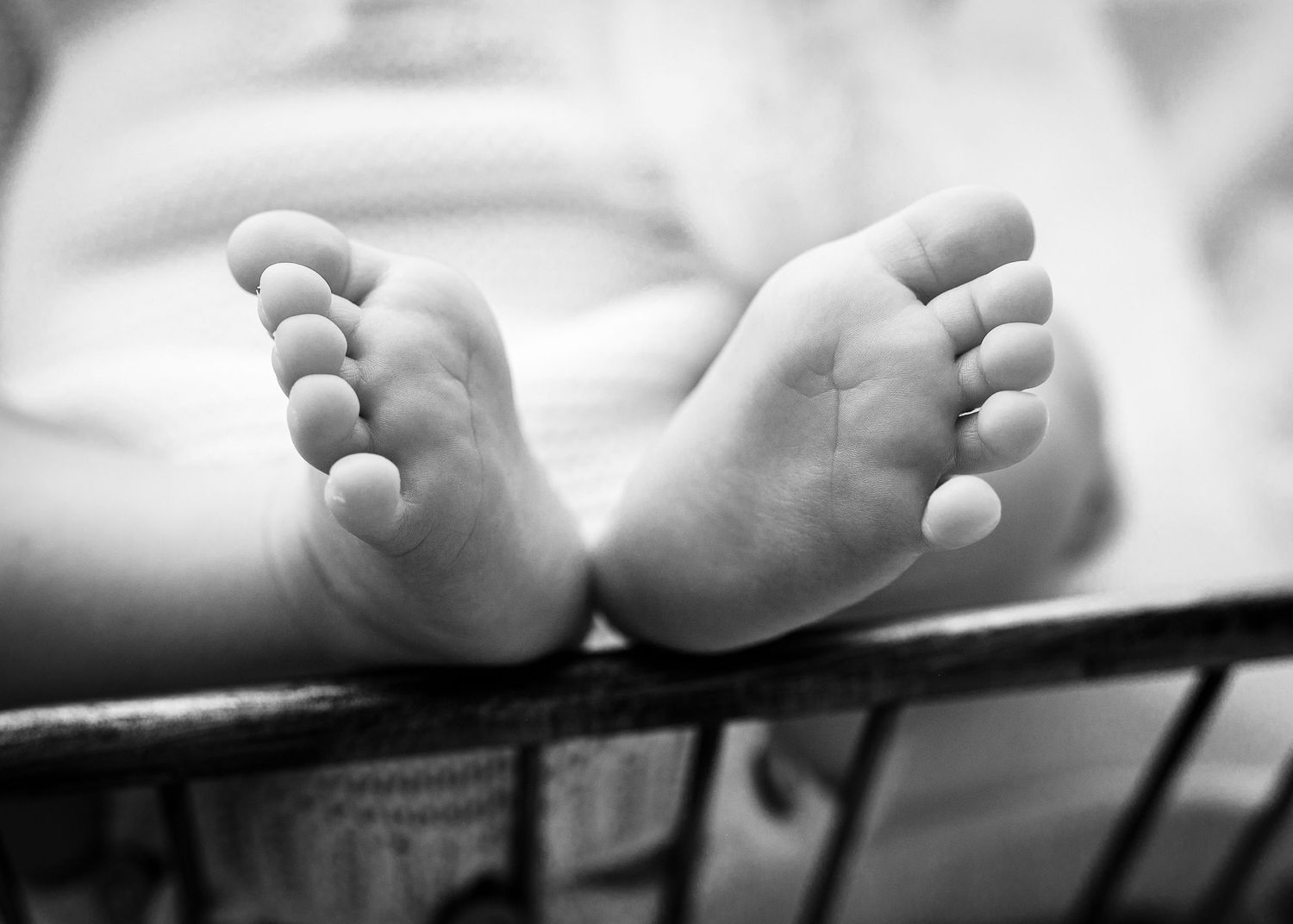 Close-up black and white detail shots of tiny baby feet in artistic composition.