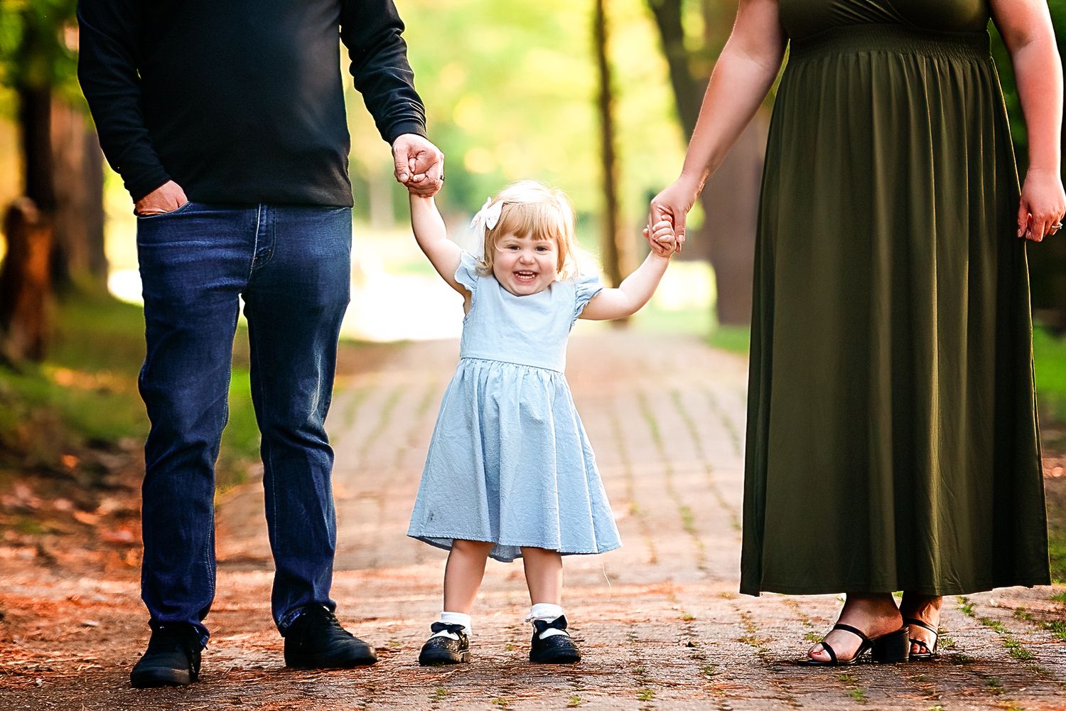 Cropped view of family members' legs and feet standing together on a brick pathway.