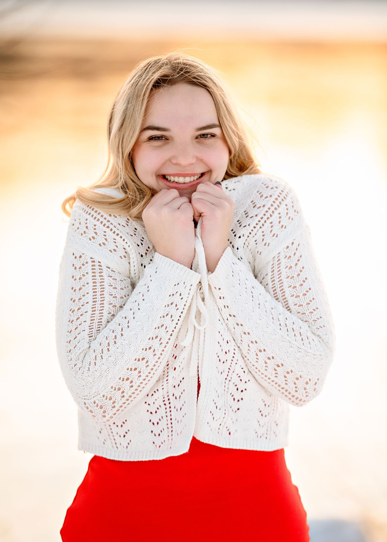 A joyful pose in a white crochet sweater and red skirt.