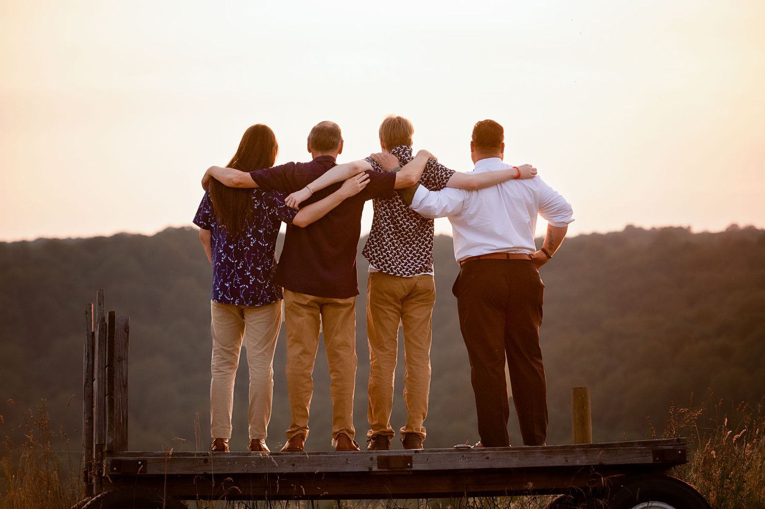 Group standing together on a wooden dock at sunset with hills in background.
