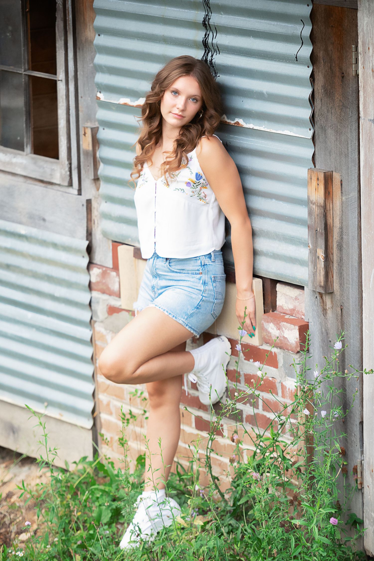 A casual summer portrait against a rustic building with corrugated metal siding.