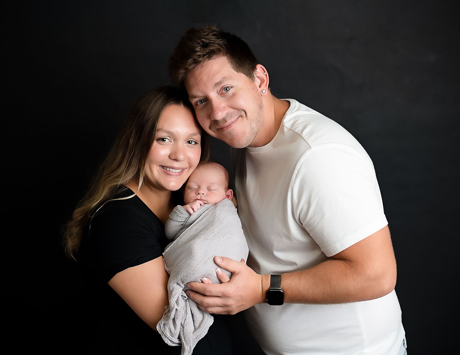 Intimate family photo session with black background and matching outfits.