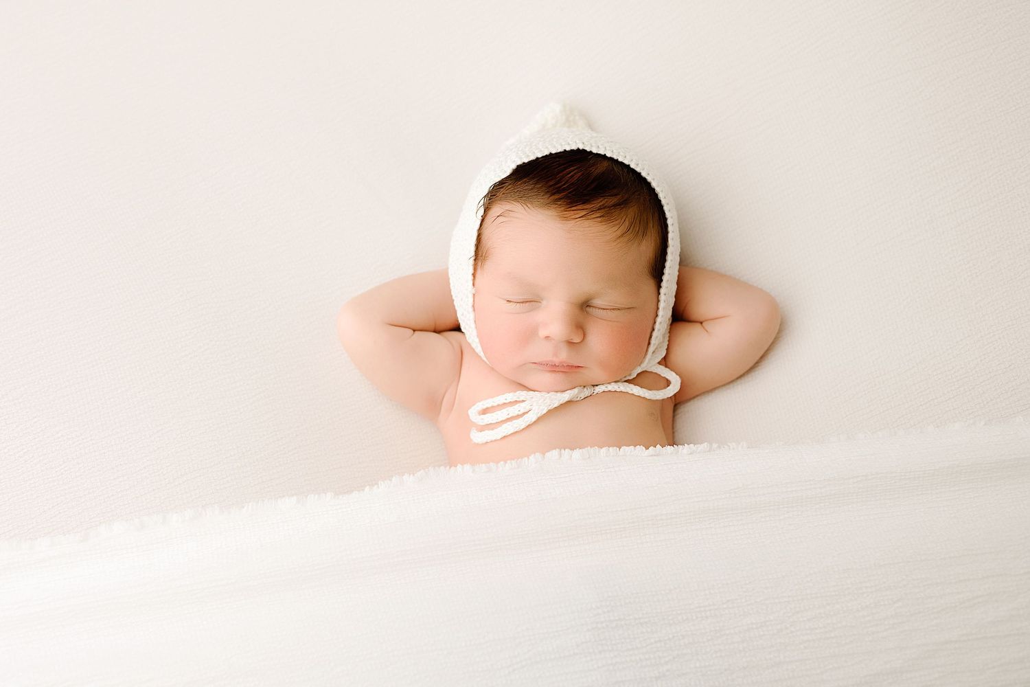 Artistic newborn photography series with baby sleeping on white textured background.