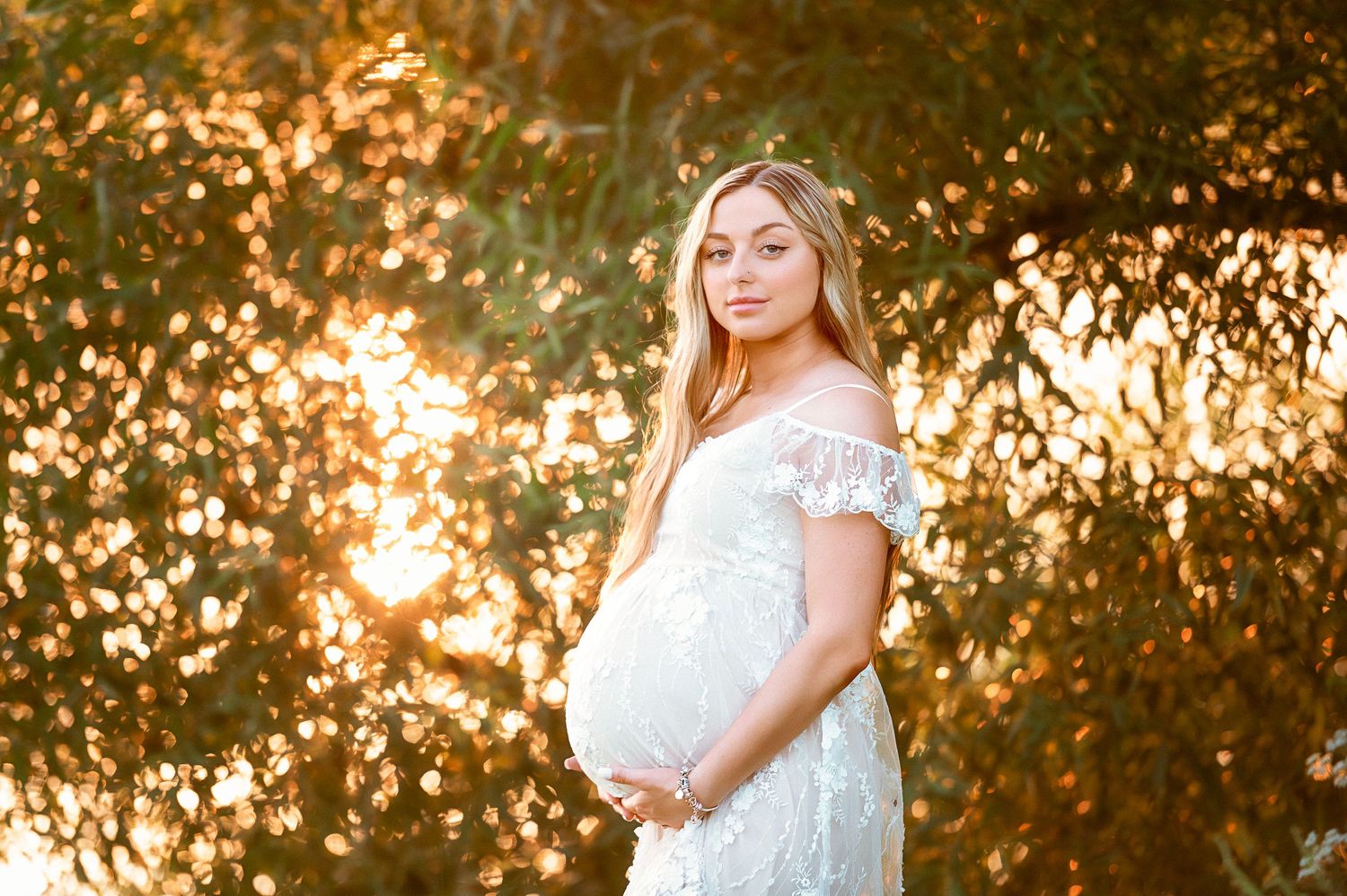 Sunset maternity session with golden backlight through trees.