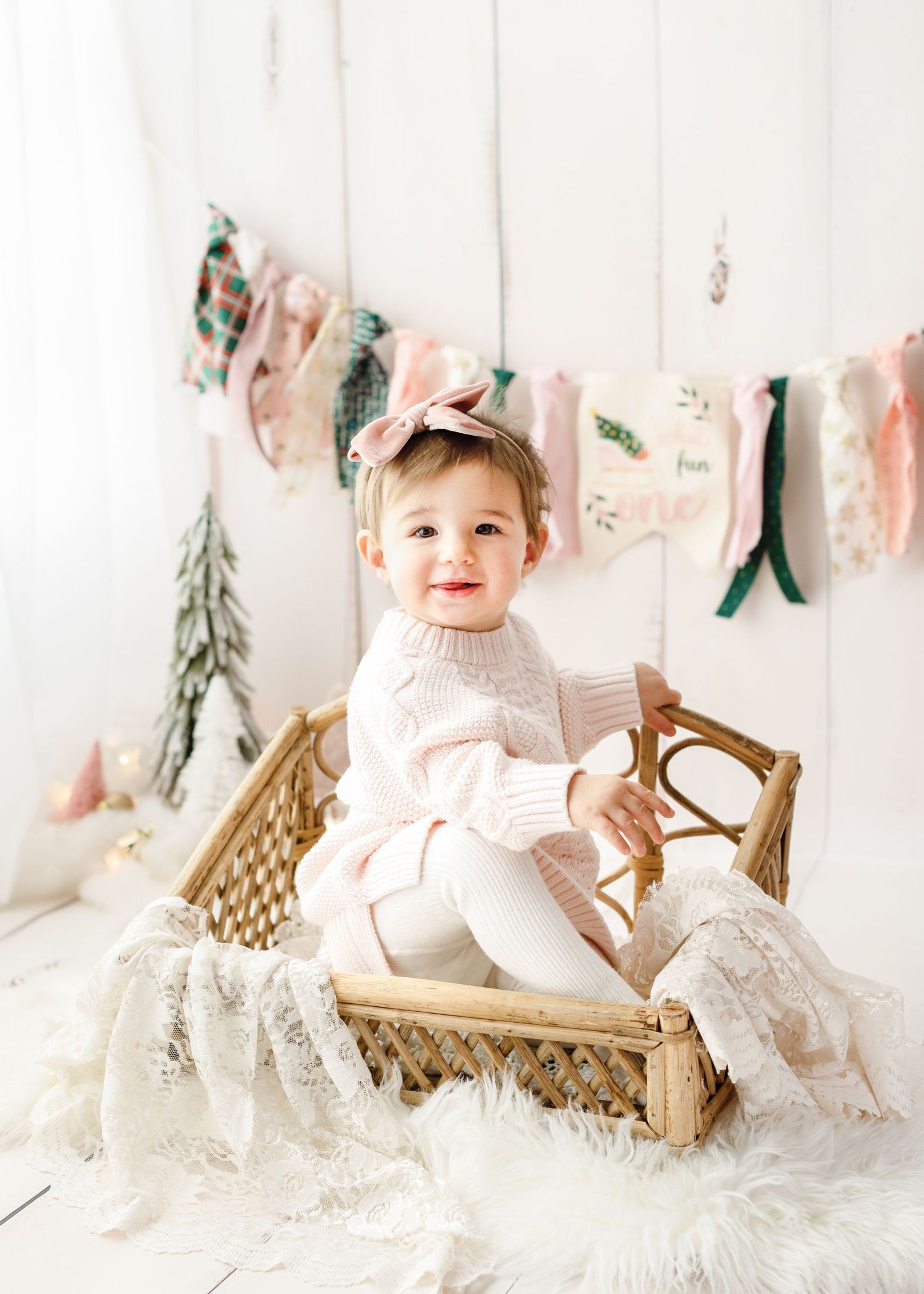 Holiday themed photo setup with white bench, lace details and festive garland.