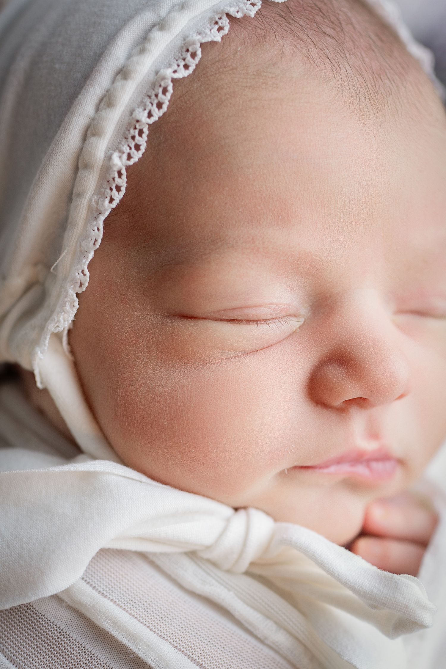 A sleeping newborn baby wrapped in soft white fabric, shown in a series of close-up profile views.