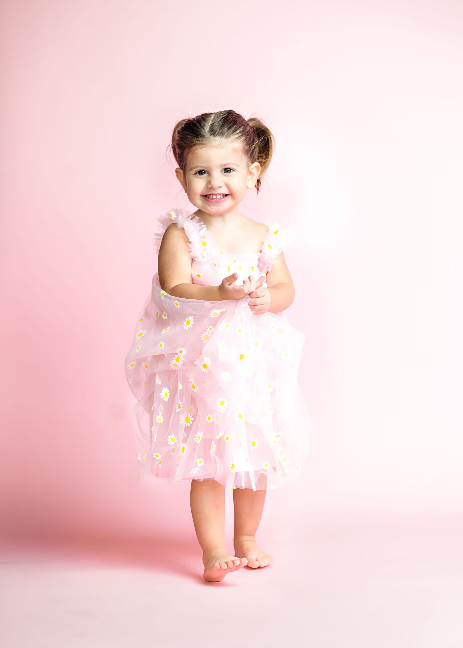 Pink-themed studio photoshoot with soft lighting and pastel decorative elements.