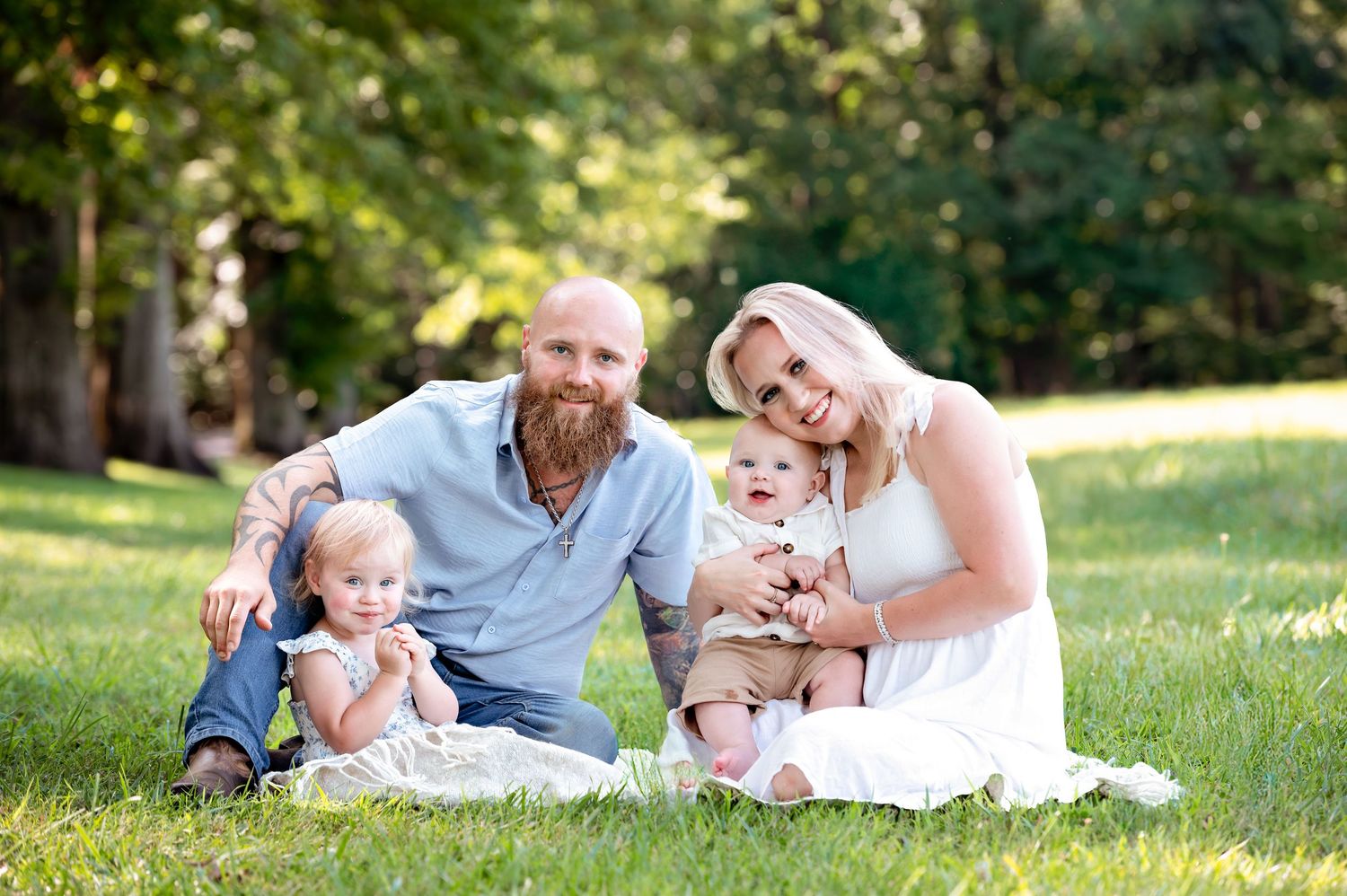 Family lounging together on blankets in a peaceful park setting.