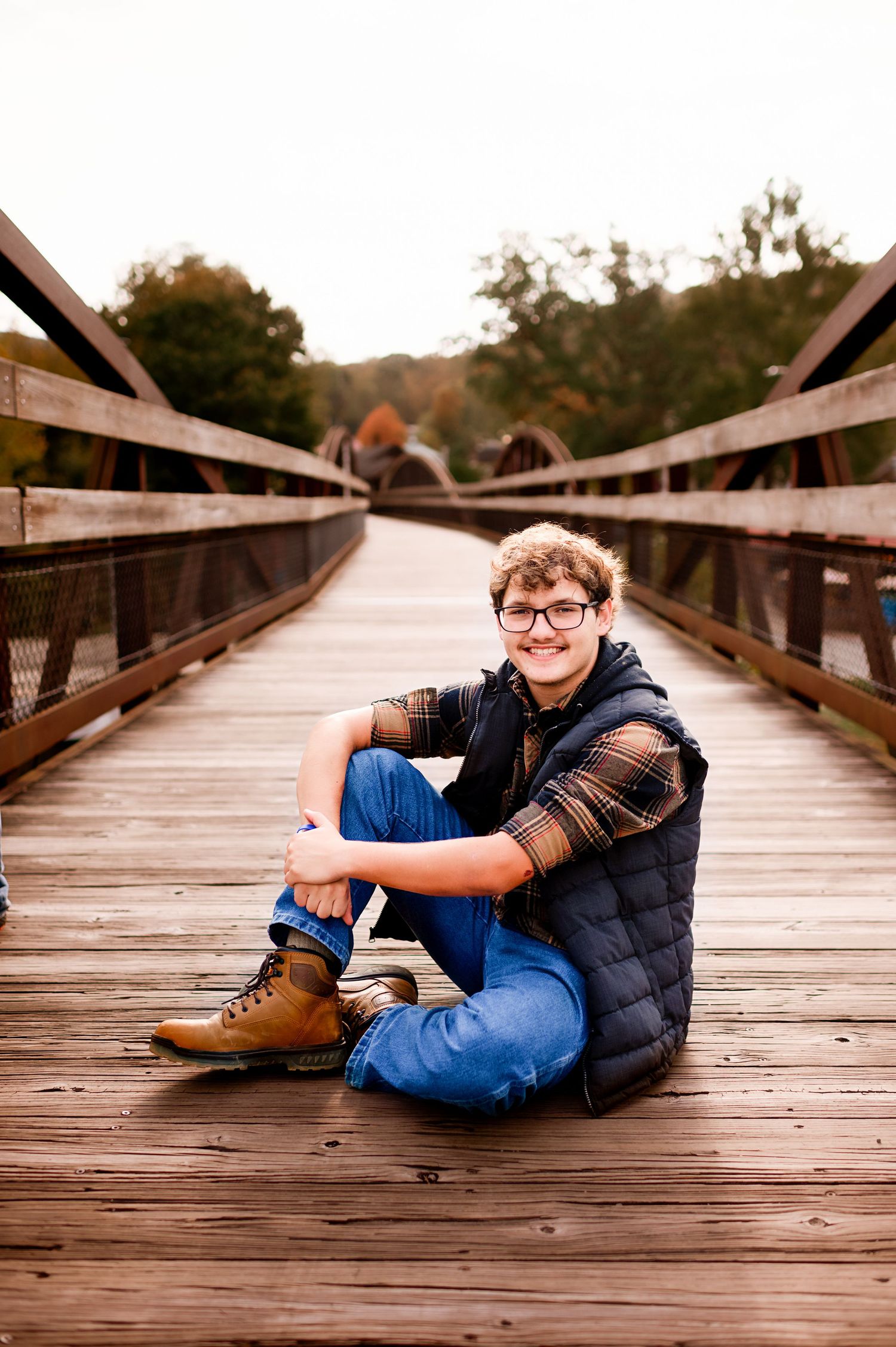 Portrait session on a wooden bridge with casual poses and autumn scenery.