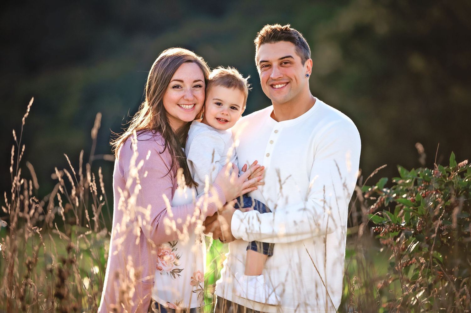 Family enjoying a tender moment together in a sunlit field at sunset.