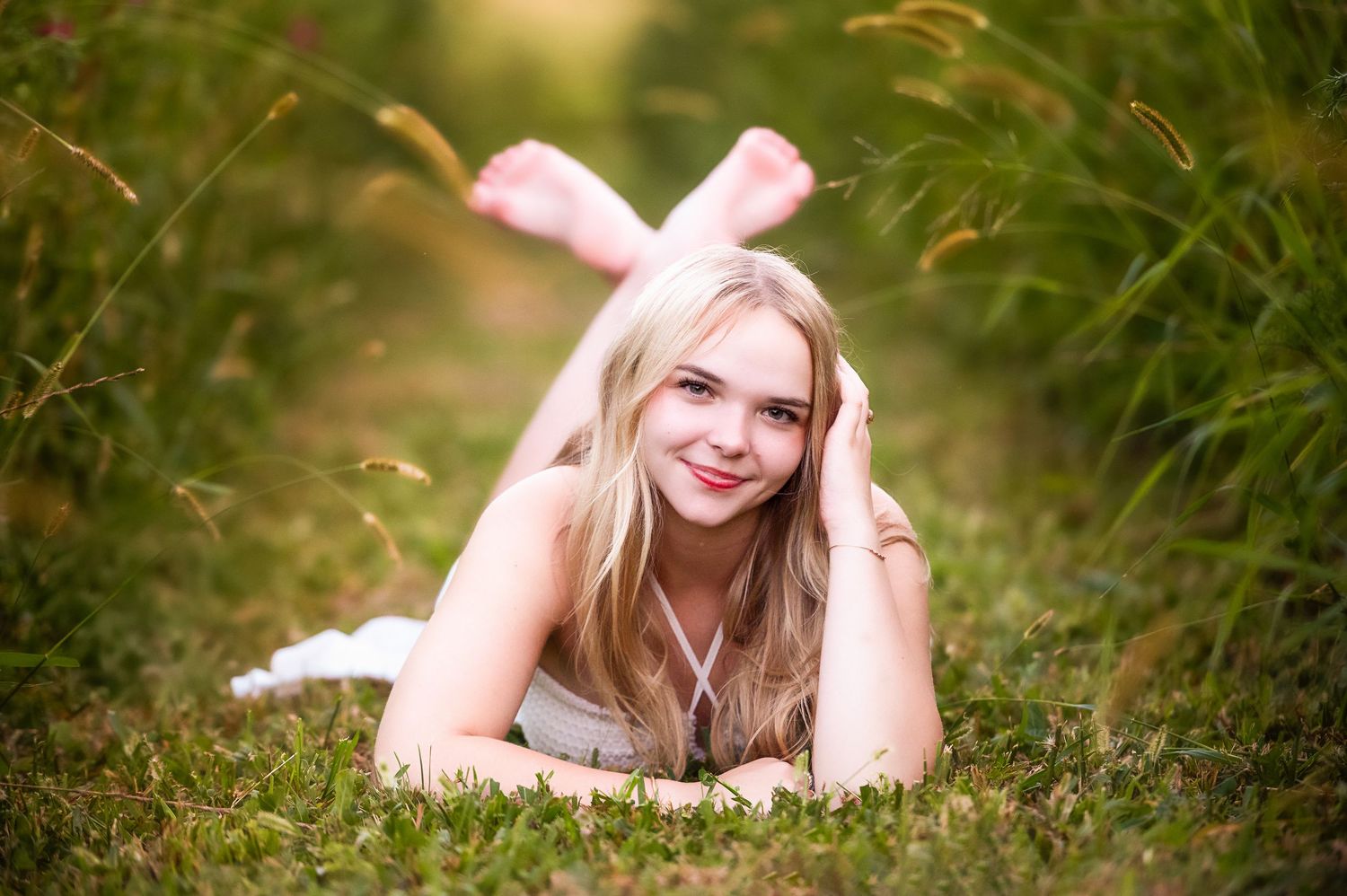 A person lying in a field of tall grass during golden hour.