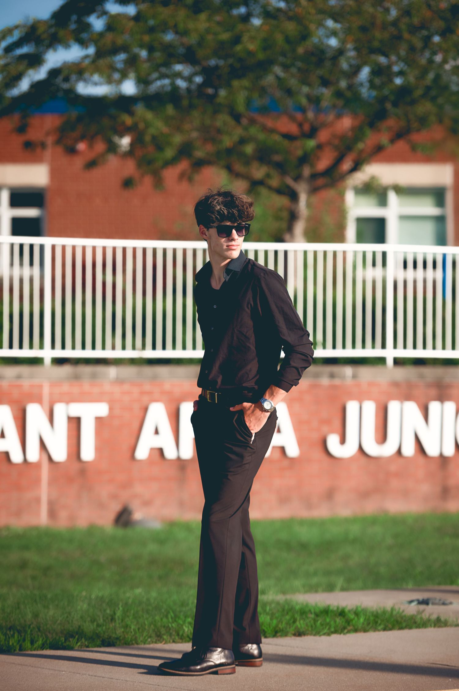Artistic portrait with sunglasses against brick building and text.