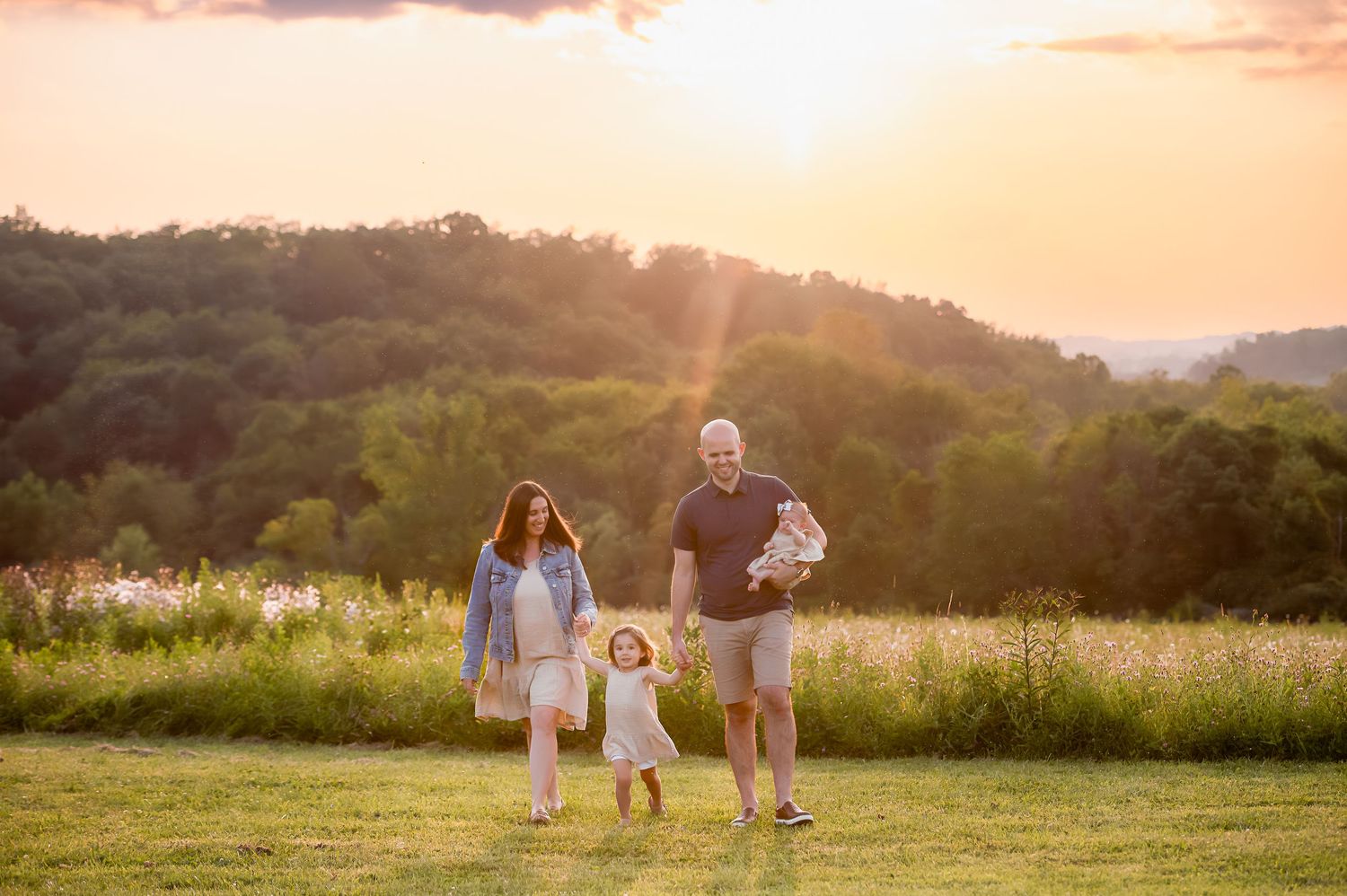 Family enjoying quality time together in meadow during golden sunset.