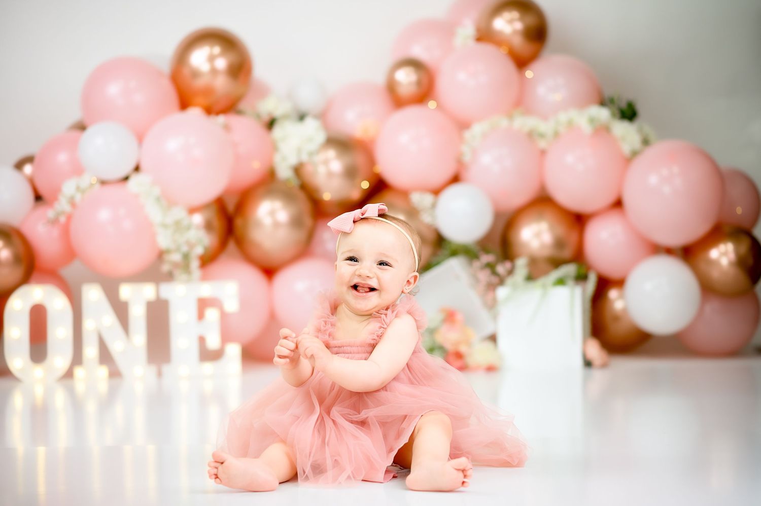 Elegant pink balloon garland with metallic accents and 'ONE' signage.
