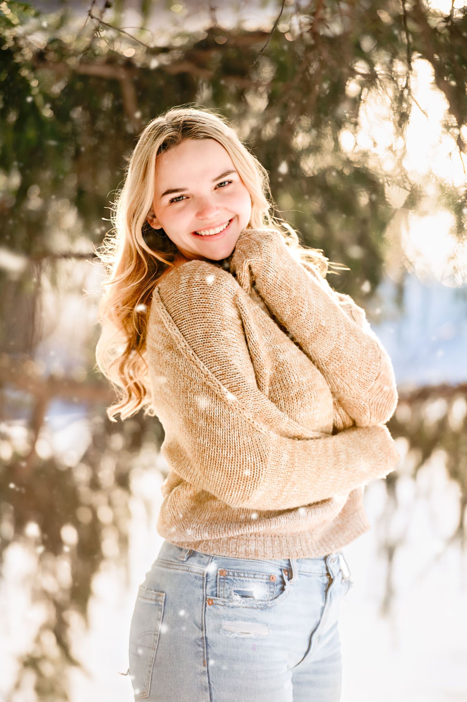 A winter portrait featuring a beige knit sweater against snowy trees.
