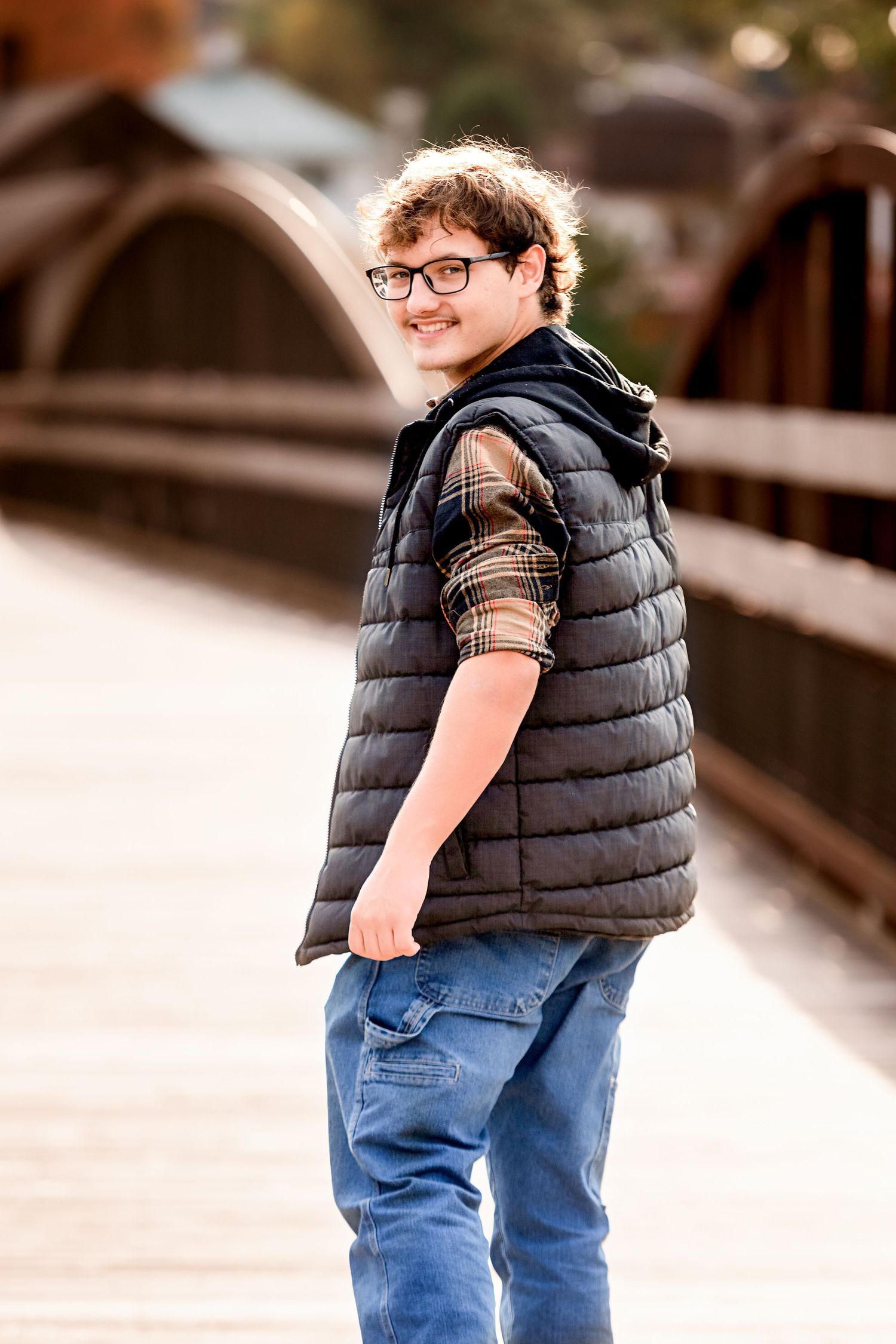 Casual portraits featuring a black puffy vest and plaid shirt against neutral background.