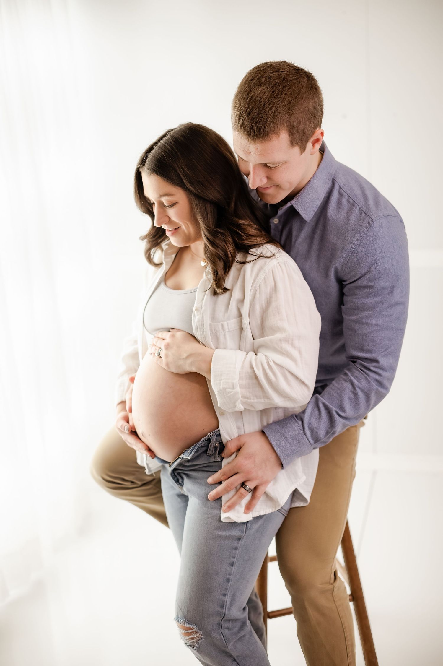 Series of intimate maternity poses with couple in neutral colored clothing.