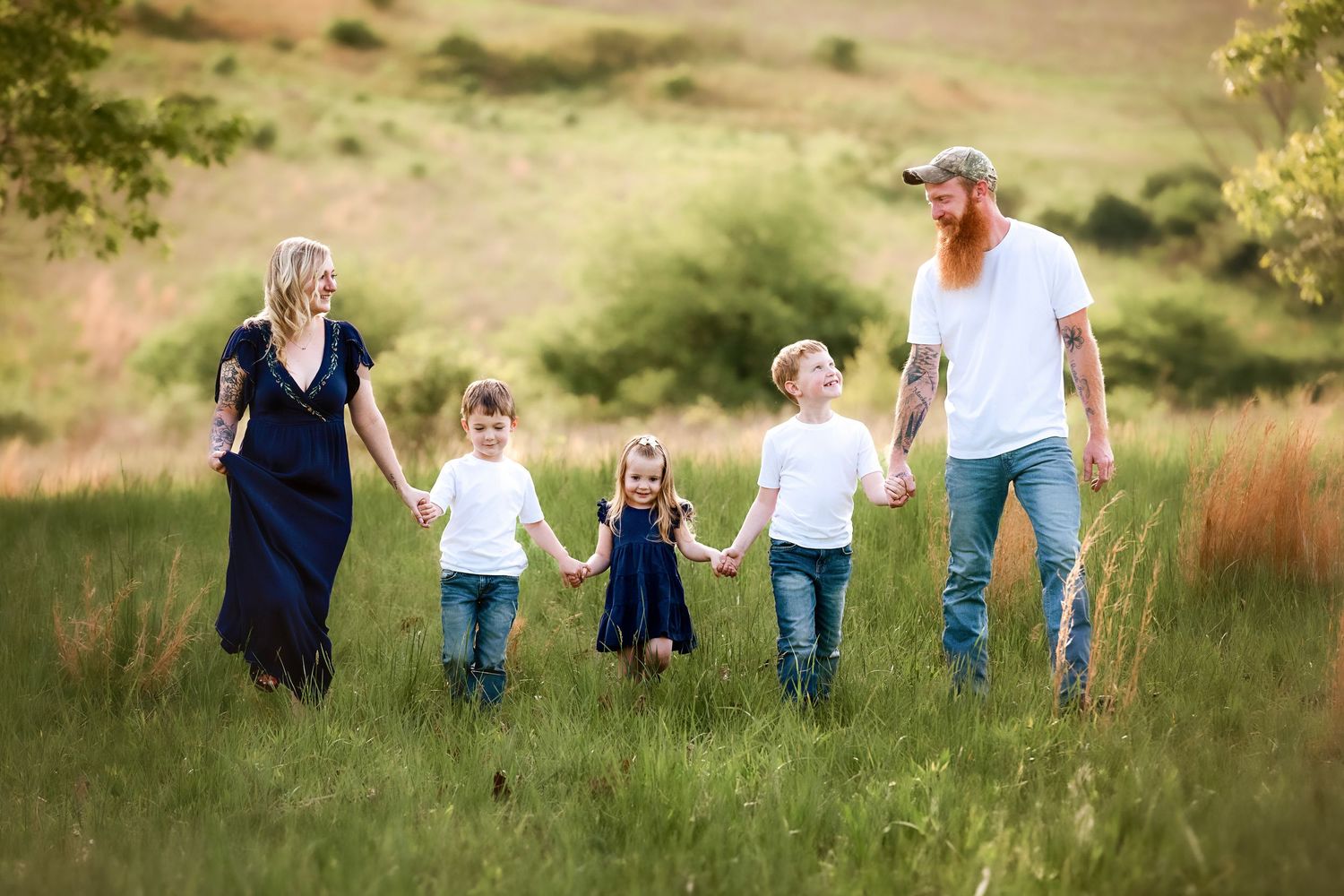 Group walking together through a scenic meadow with rolling hills in the background.