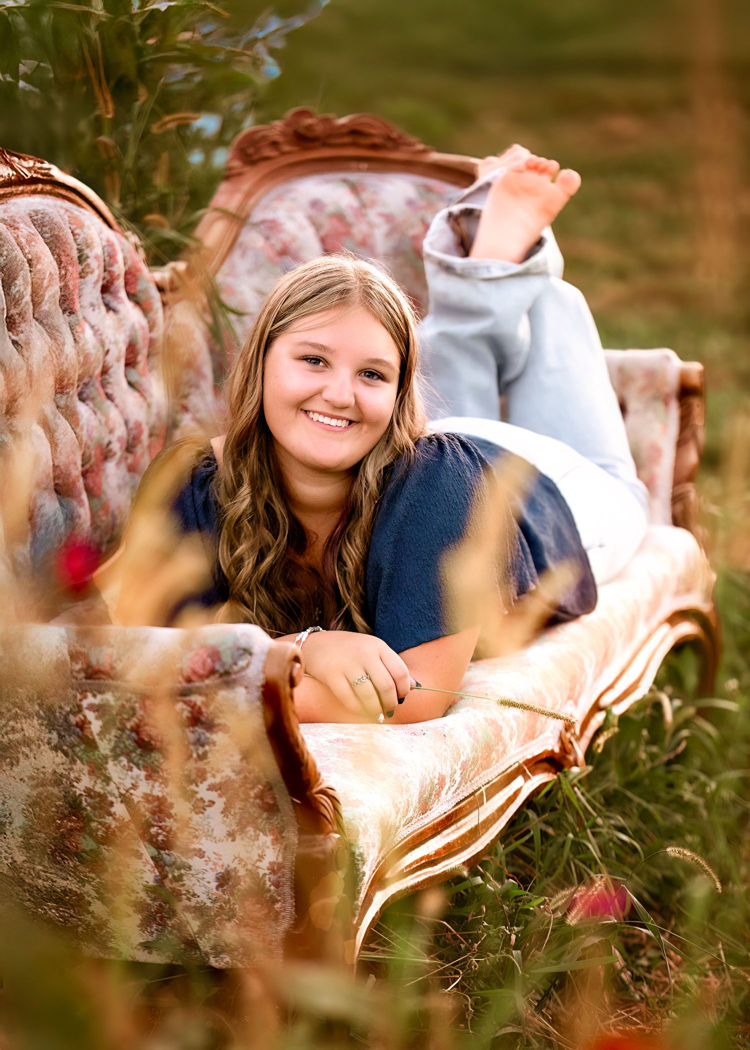 A relaxed outdoor portrait among tall grass and wildflowers.