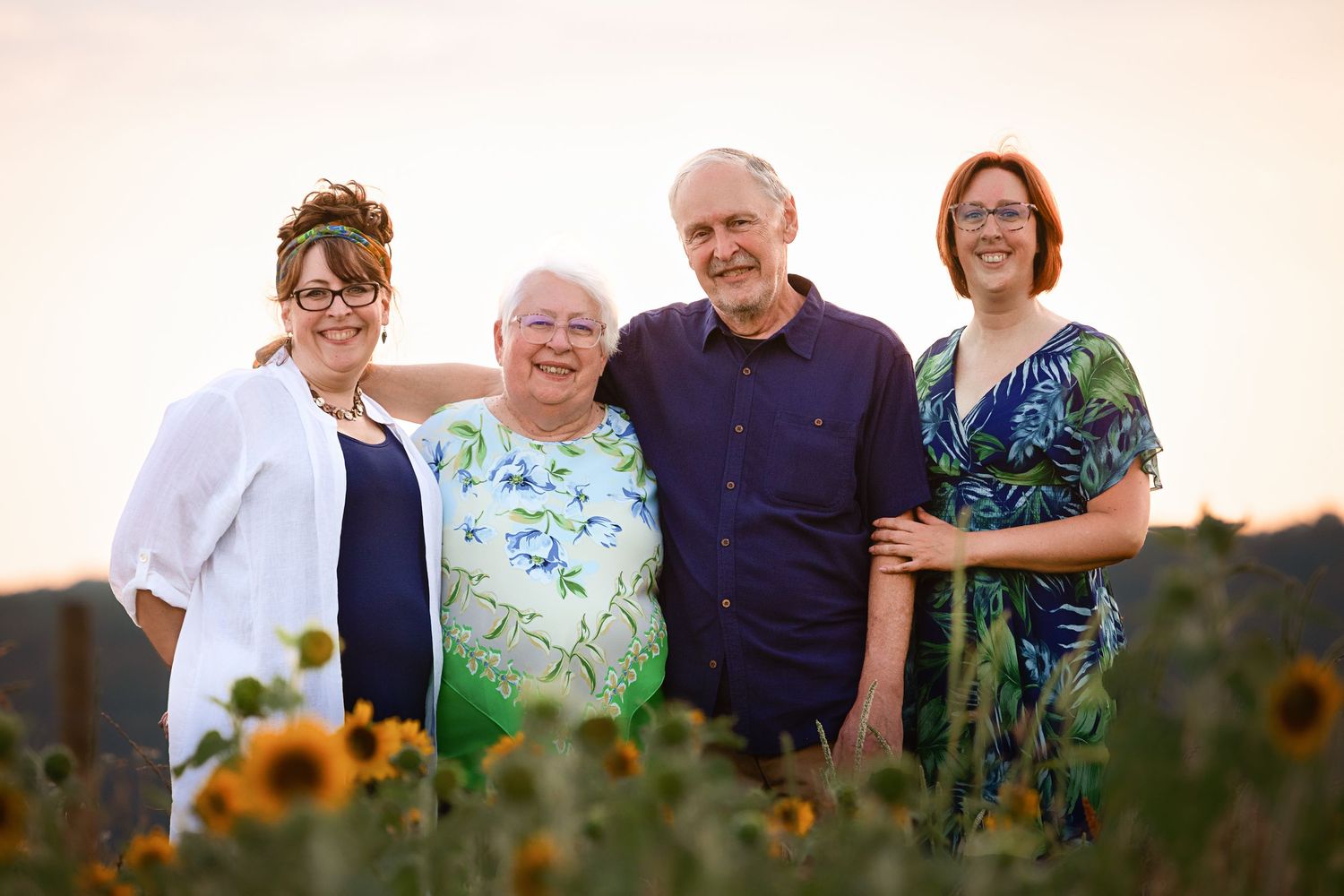 Extended family portrait in a sunflower field during golden hour.